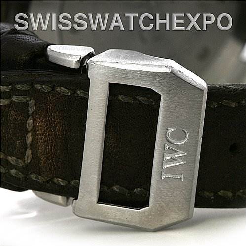 The image shows a close-up of the clasp and strap of the Pilot model watch by IWC, featuring a leather band and a metal buckle with the IWC logo.