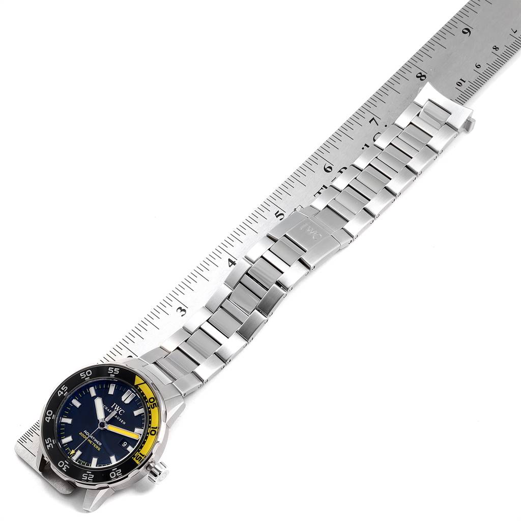 The image shows the IWC Aquatimer IW356801 Men
s Stainless Steel Black Dial IW356801 Men
s Stainless Steel Black Dial watch laid flat next to a ruler, displaying its face and metal bracelet.