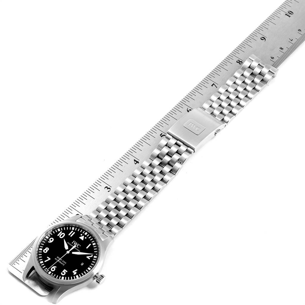 The IWC Pilot IW327015 Men's Stainless Steel Black Dial IW327015 Men's Stainless Steel Black Dial model watch is displayed flat, showing the face, bezel, crown, and metal bracelet with clasp against a ruler for scale.