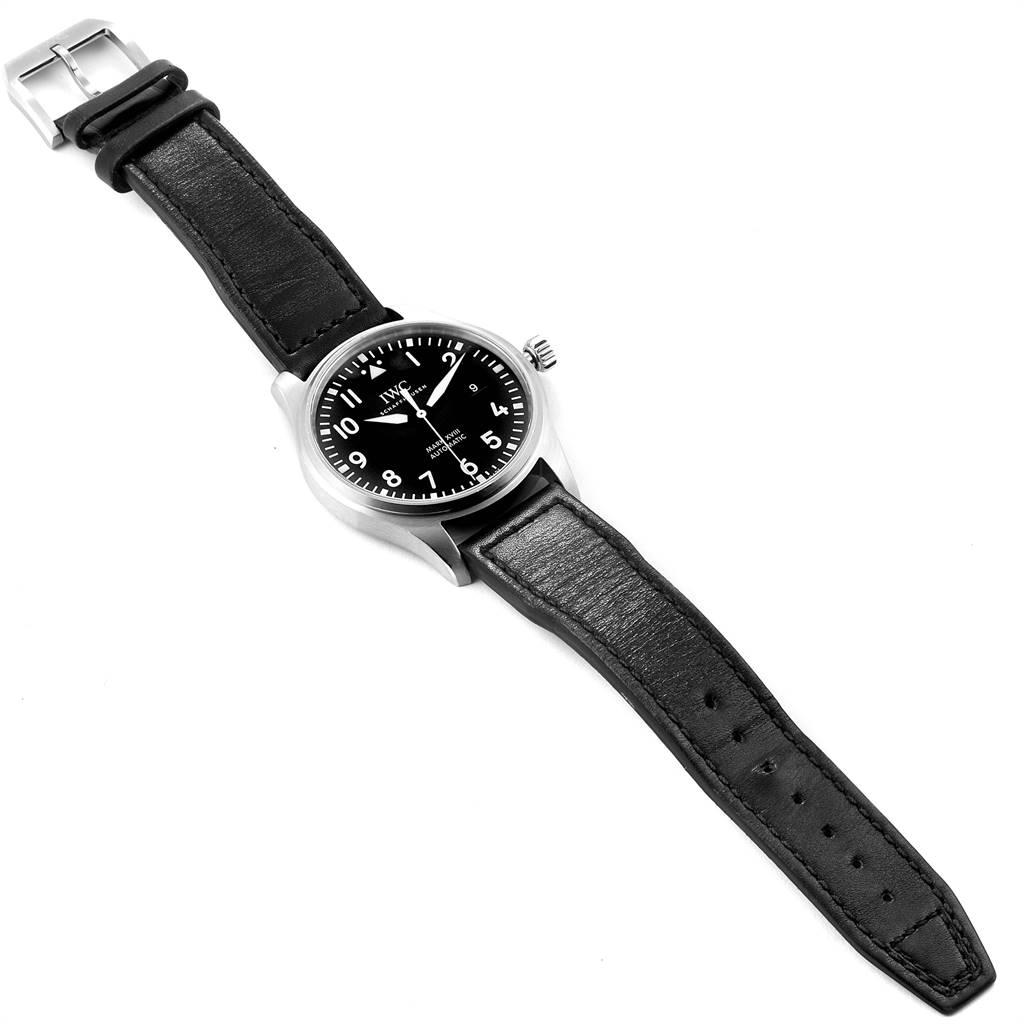 The Pilot model by IWC is shown from a top-down view, displaying the face, case, strap, and buckle.