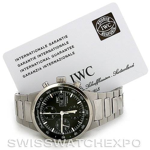 The image shows a front angle view of an IWC GST IW3707-008 Men's Stainless Steel Black Dial IW3707-008 Men's Stainless Steel Black Dial model watch with its international guarantee card in the background.