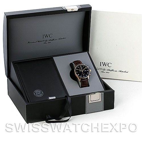 The image shows an IWC Portuguese IW3714-15 Men's Rose Gold Black Dial IW3714-15 Men's Rose Gold Black Dial model watch in its open box, featuring a leather strap and a black dial, with an accompaying booklet or accessory.