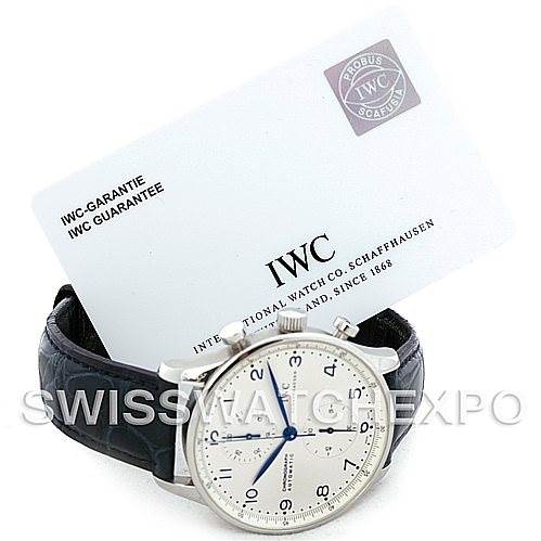 This image shows an IWC Portuguese IW371417 Men
s Stainless Steel Silver Dial IW371417 Men
s Stainless Steel Silver Dial watch at an angle, displaying the dial and leather strap, along with the IWC guarantee card in the background.