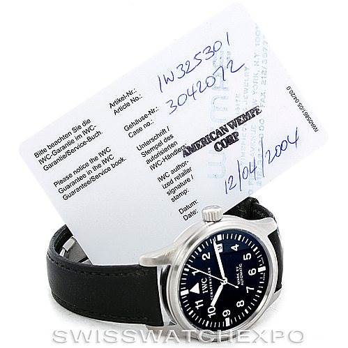 The image shows an IWC Pilot IW325301 Men's Stainless Steel Black Dial IW325301 Men's Stainless Steel Black Dial model watch at a slight angle, highlighting its black leather strap and black dial, with its guarantee card.