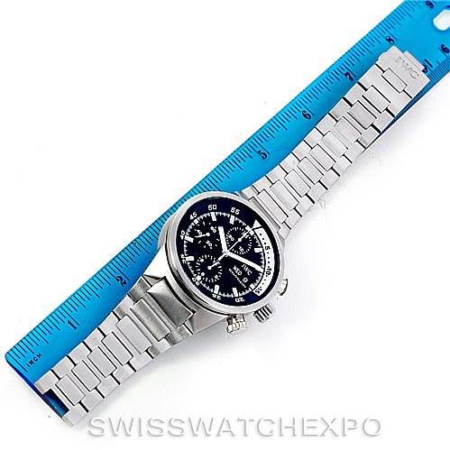 The IWC Aquatimer IW371928 Men's Stainless Steel Black Dial IW371928 Men's Stainless Steel Black Dial watch is shown from a top-down angle, highlighting its face and metal bracelet against a blue ruler.