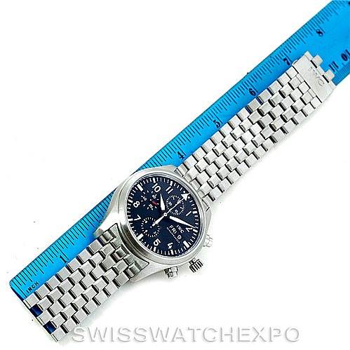 The IWC Pilot IW370607 Men's Stainless Steel Black Dial IW370607 Men's Stainless Steel Black Dial model watch is shown from a top-down angle, displaying the face and the metal bracelet band alongside a ruler for scale.