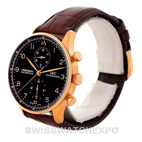 This image shows an IWC Portuguese IW371415 Men's Rose Gold Black Dial IW371415 Men's Rose Gold Black Dial model watch from a front-left angle, highlighting its black dial, gold case, and brown leather strap.