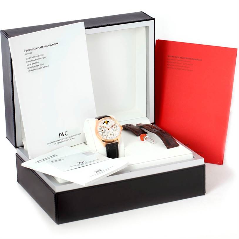 The image shows an IWC Portuguese IW502213 Men
s Rose Gold Silver Dial IW502213 Men
s Rose Gold Silver Dial model watch in a box, along with manuals, additional straps, and an adjustment tool.