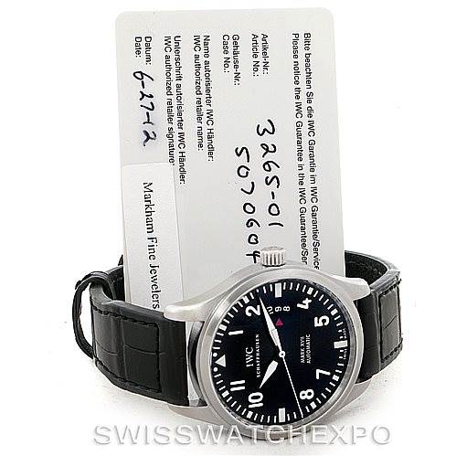 The image shows an IWC Pilot IW326501 Men's Stainless Steel Black Dial IW326501 Men's Stainless Steel Black Dial watch, front view, with a visible black leather strap and warranty card behind it.