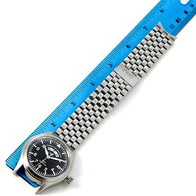 This image shows an IWC Pilot IW325102 Men's Stainless Steel Black Dial IW325102 Men's Stainless Steel Black Dial model watch with a metal bracelet and a blue ruler for measurement.