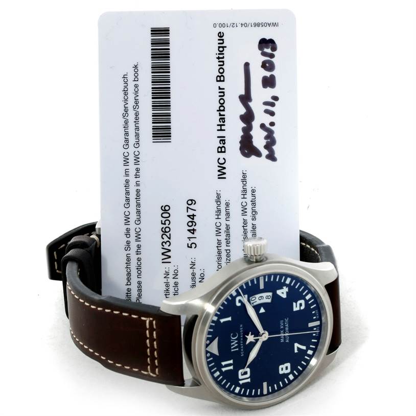 The image shows an IWC Pilot IW326506 Men's Stainless Steel Blue Dial IW326506 Men's Stainless Steel Blue Dial model watch with a blue dial and brown leather strap, alongside warranty documentation.