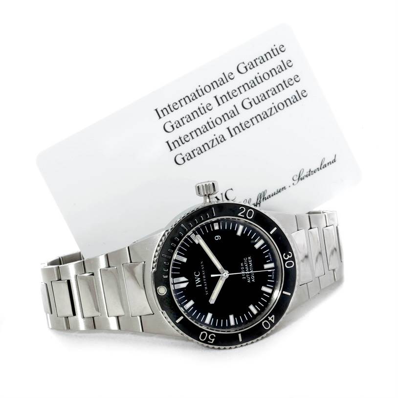 The IWC GST IW353602 Men's Stainless Steel Black Dial IW353602 Men's Stainless Steel Black Dial model watch is shown at an angle displaying the front dial and metal bracelet, with a guarantee card in the background.