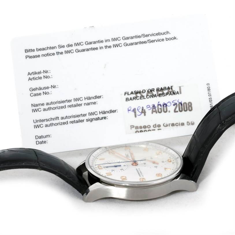 The image shows the side view of an IWC Portuguese IW371445 Men's Stainless Steel Silver Dial IW371445 Men's Stainless Steel Silver Dial watch with a visible dial, case, and black strap, alongside its guarantee/service book.