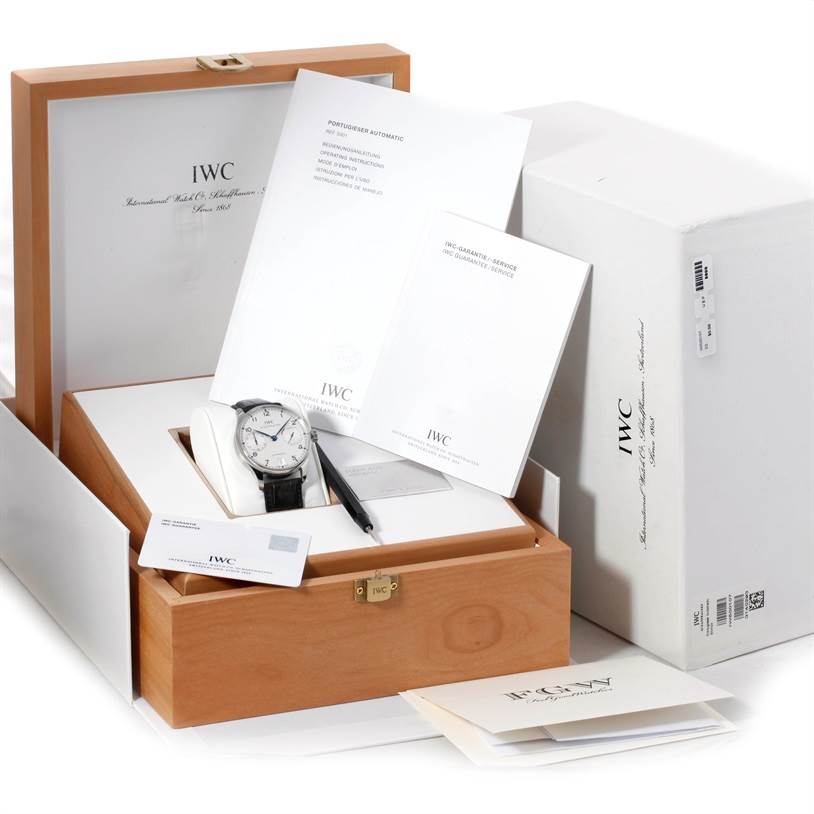 The image shows the IWC Portuguese IW500107 Men's Stainless Steel Silver Dial IW500107 Men's Stainless Steel Silver Dial model watch at an angled view inside its wooden box, along with its manuals and packaging.