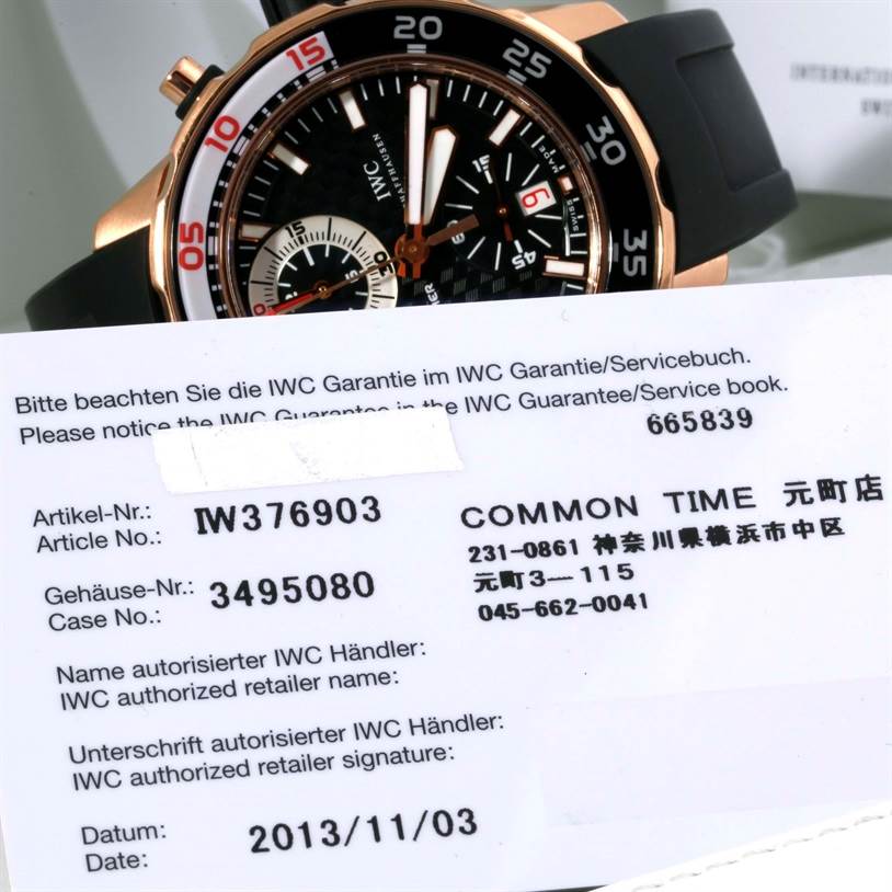 The image shows the IWC Aquatimer IW376903 Men's Rose Gold Black Dial IW376903 Men's Rose Gold Black Dial watch at an angle displaying its face and part of its band, along with warranty information.