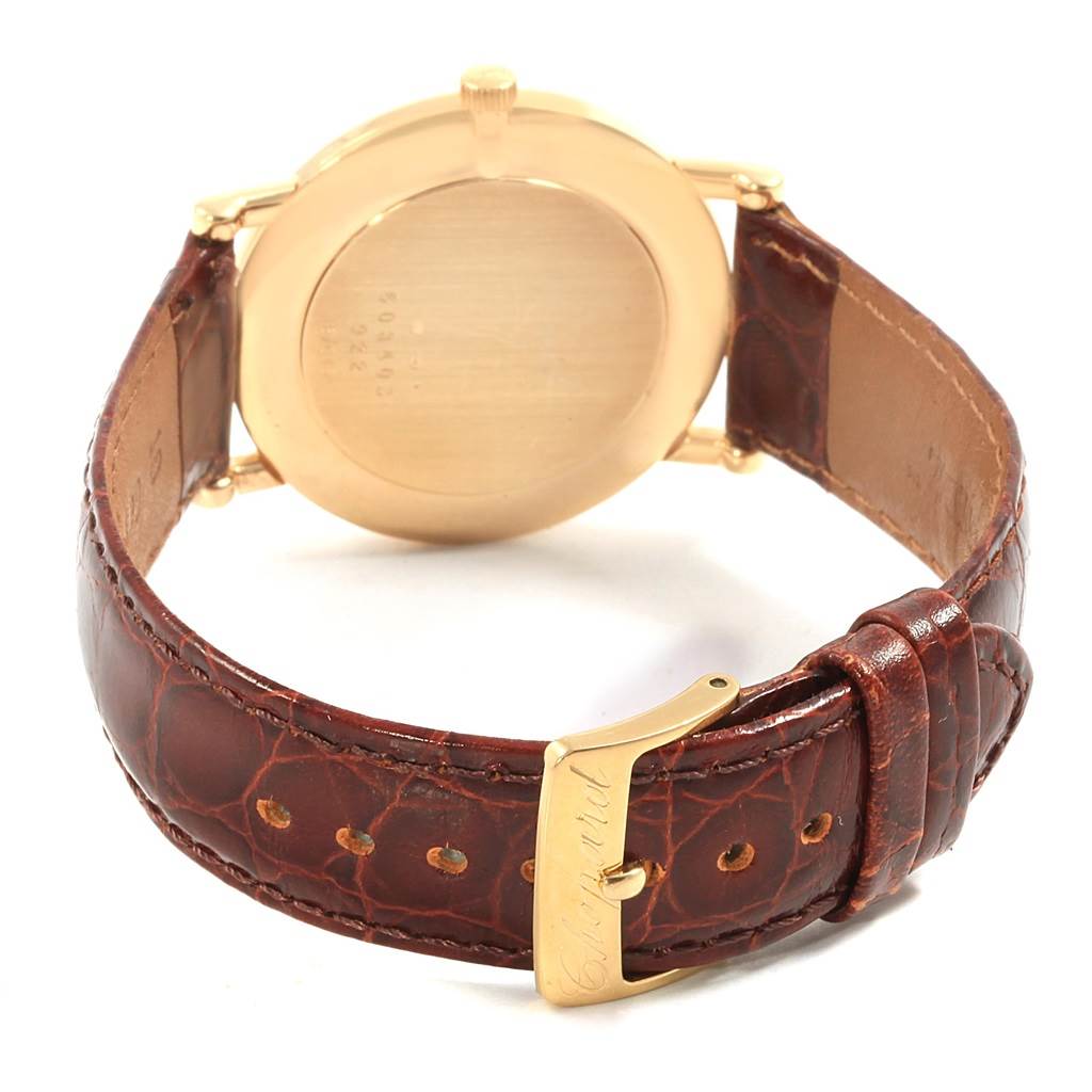 The image shows the back view of the Chopard Classique 16/3154 Men's Yellow Gold White Dial 16/3154 Men's Yellow Gold White Dial watch, highlighting its gold case and brown leather strap with a Chopard-engraved buckle.