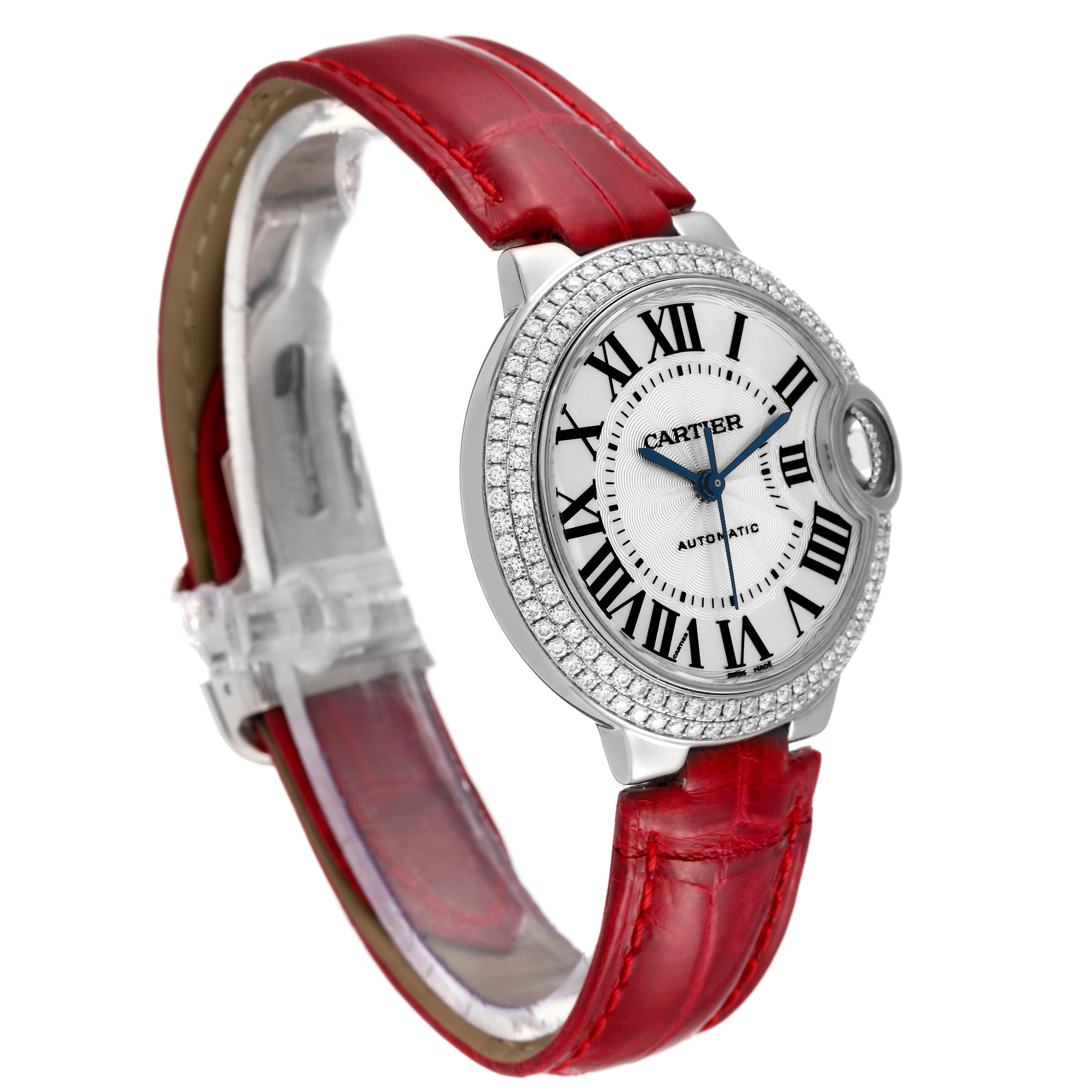 The image shows a Cartier Ballon Bleu WE902067 Women
s White Gold Silver Dial WE902067 Women
s White Gold Silver Dial watch with a red leather strap and a diamond-encrusted bezel, viewed from an angled side.