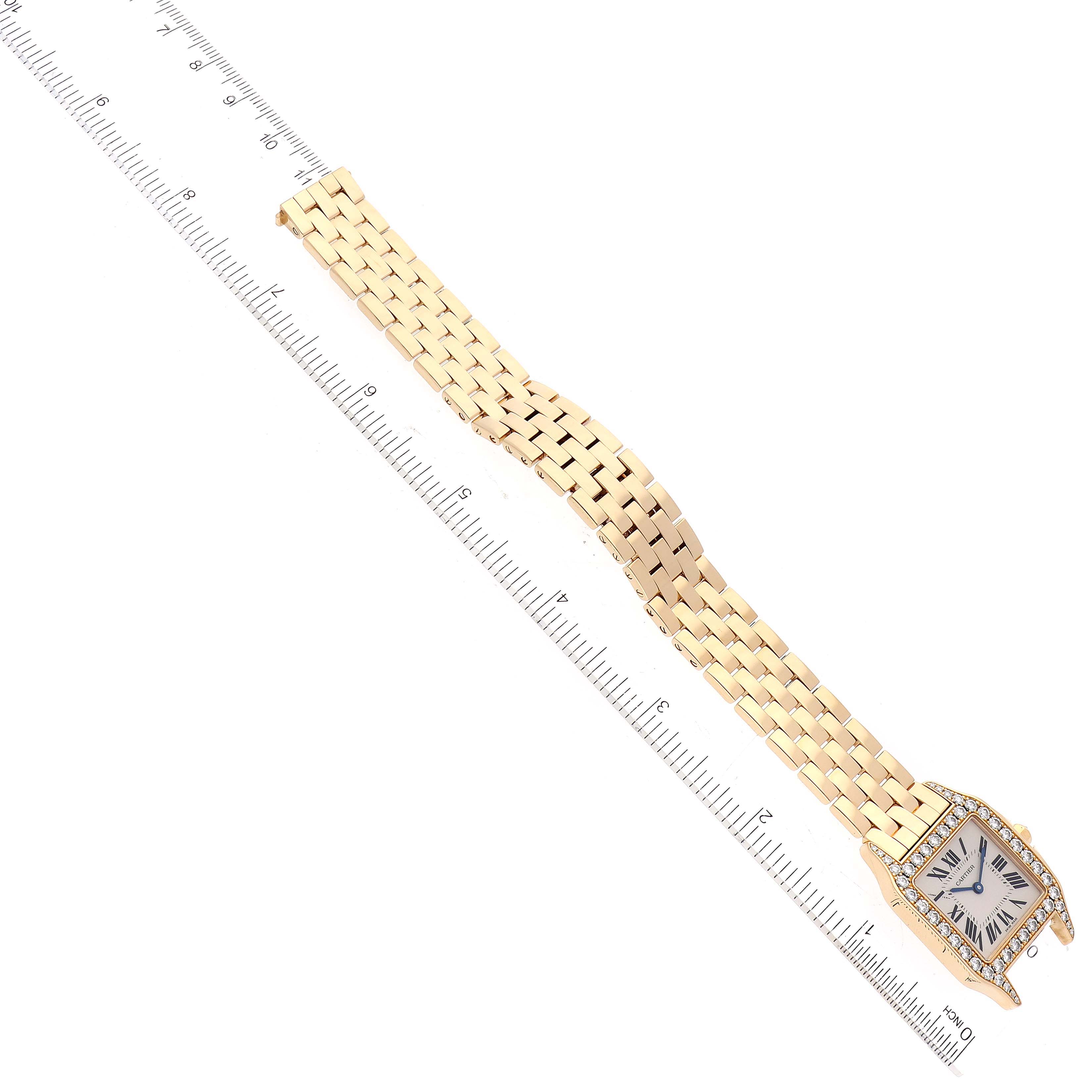 The image shows a top-down view of a Santos Demoiselle watch by Cartier with a ruler measuring the length of its gold bracelet.