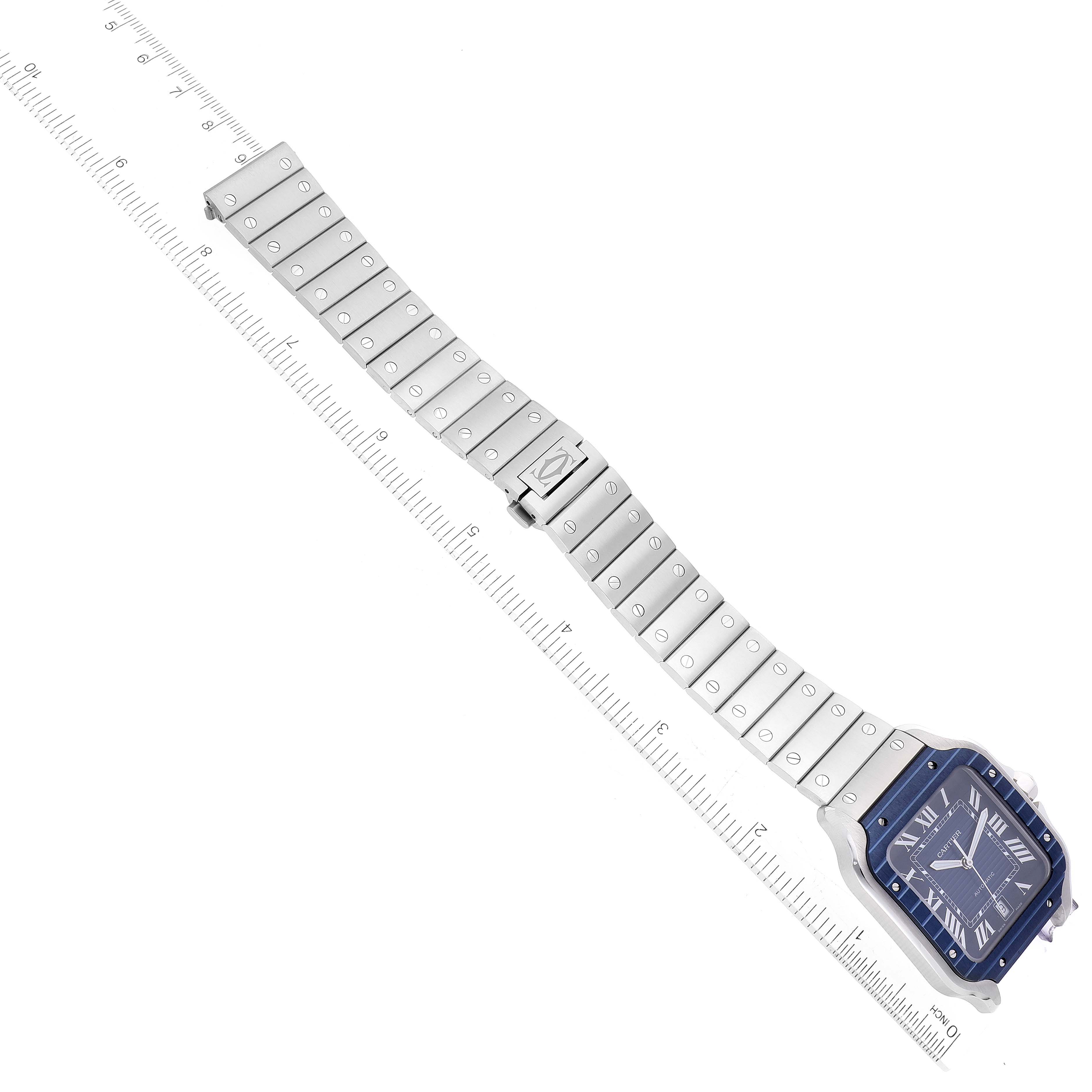 The image shows a top-down view of a Cartier Santos WSSA0048 Men
s Stainless Steel Blue Dial WSSA0048 Men
s Stainless Steel Blue Dial watch, displaying the face and full metal bracelet with a measuring ruler beside it.
