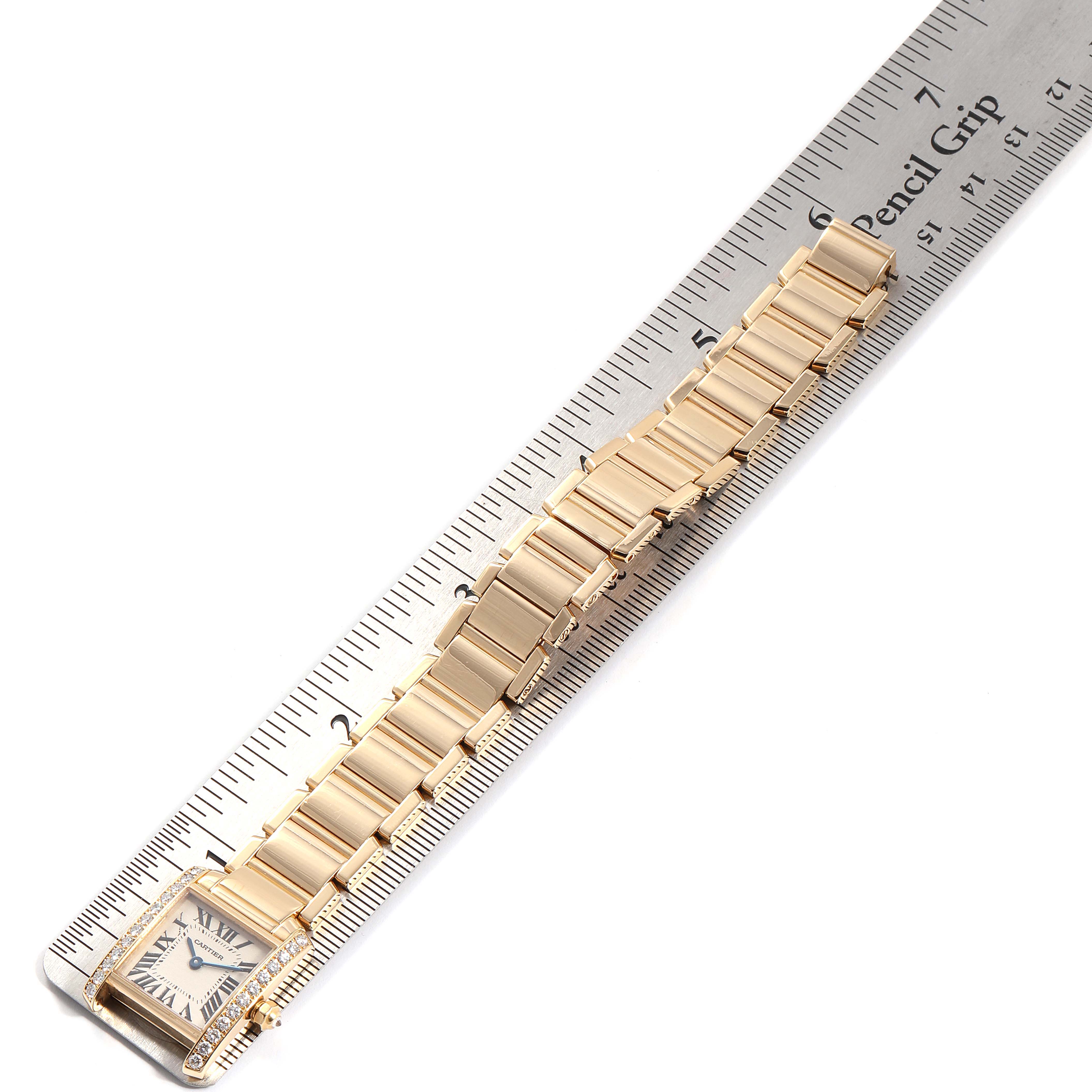 The image displays a Cartier Tank Francaise WE1001R8 Women's Yellow Gold Silver Dial WE1001R8 Women's Yellow Gold Silver Dial watch laid flat against a ruler, showing its face and bracelet.