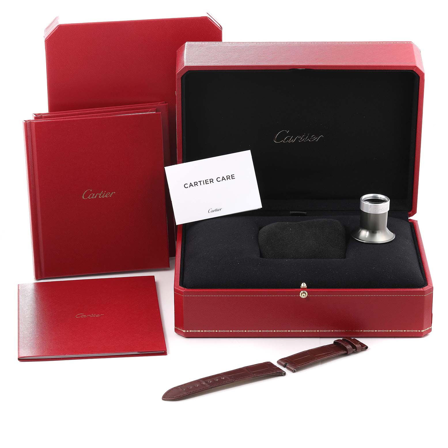 The image shows the packaging and accessories for a Cartier Tank Asymetrique WHTA0011 Men's Rose Gold Transparent Dial WHTA0011 Men's Rose Gold Transparent Dial watch, including booklets, a loupe, and a strap.