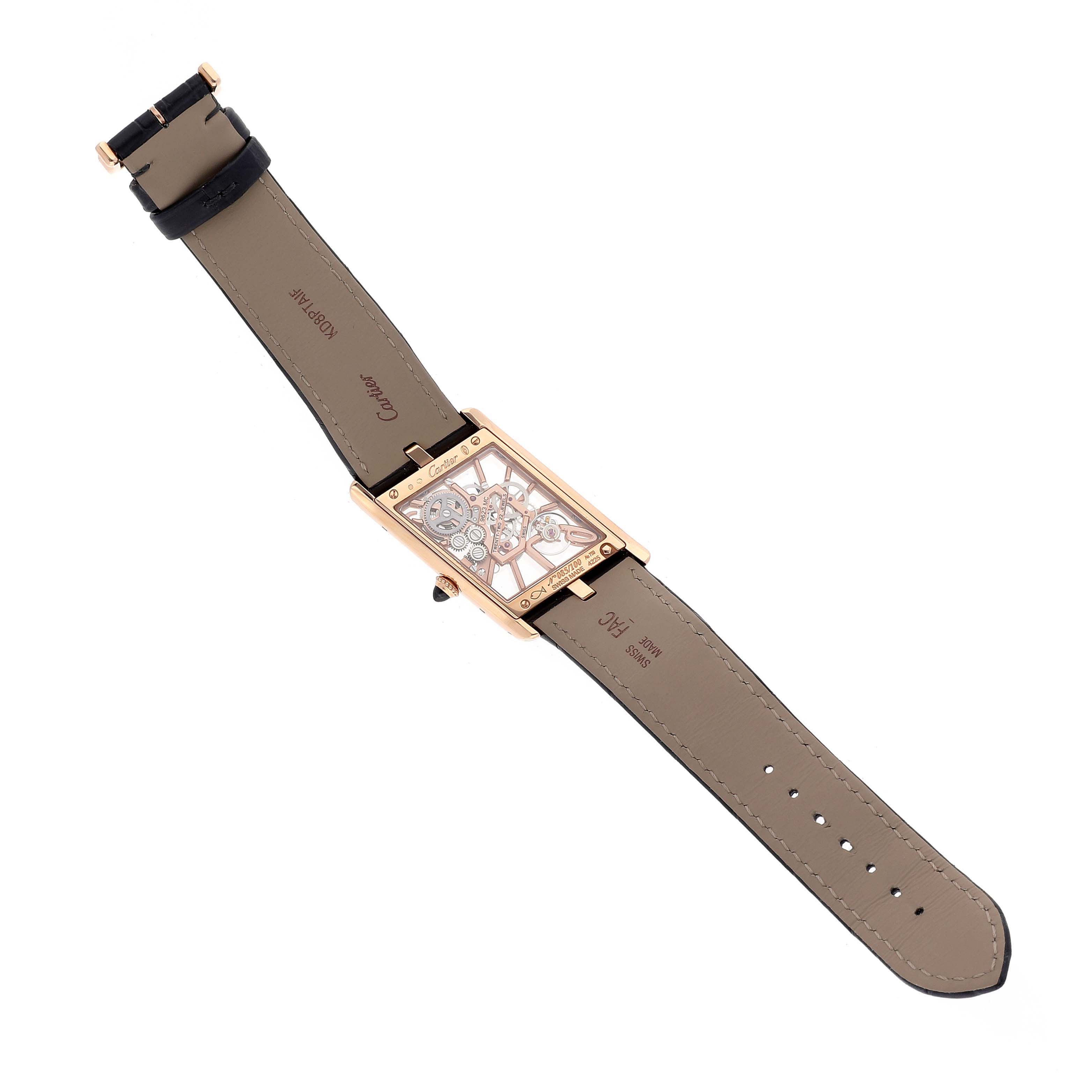 The image shows the back view of a Cartier Tank Asymétrique watch, displaying its open skeleton movement and leather strap.