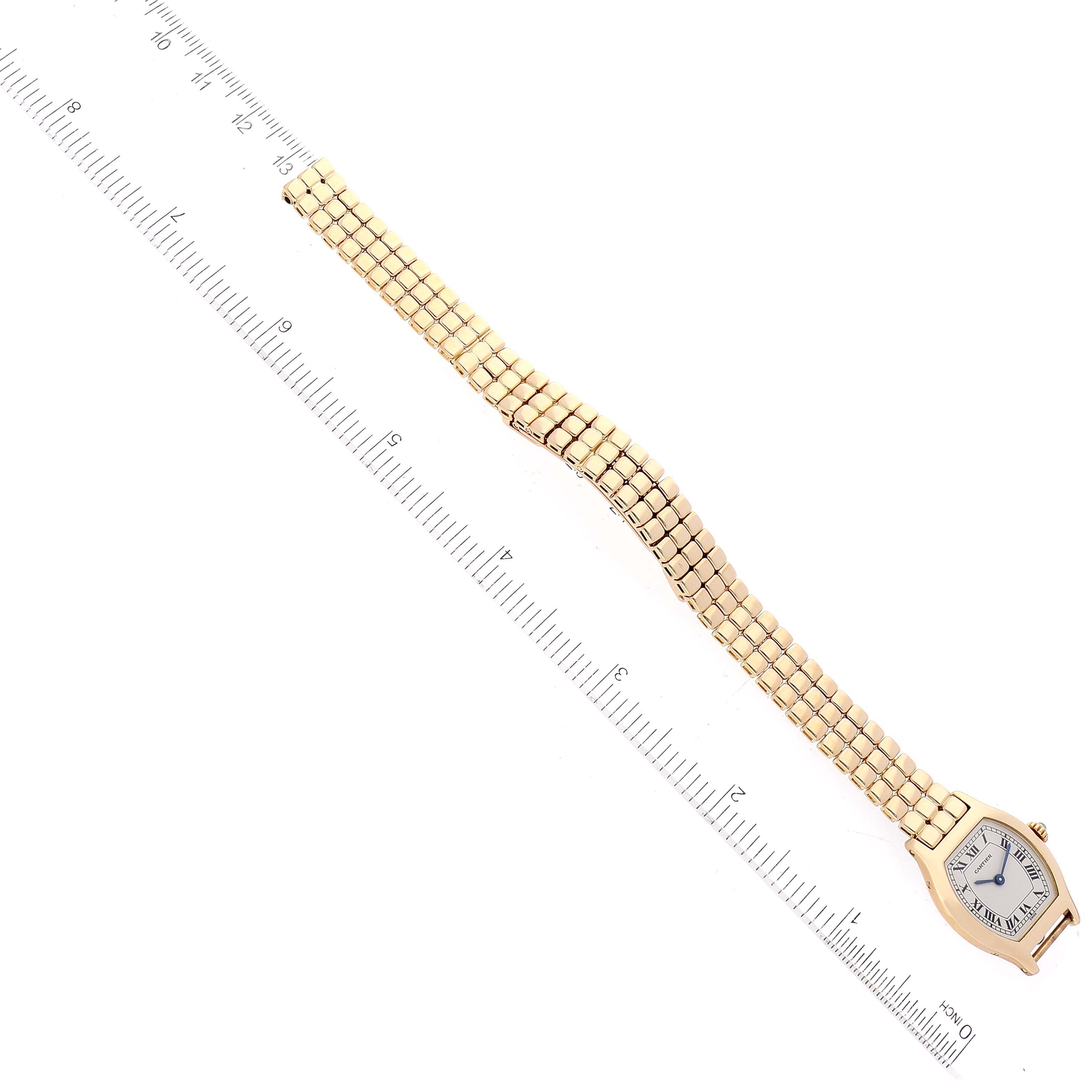 The Cartier Tortue Women's Yellow Gold Silver Dial Women's Yellow Gold Silver Dial watch is shown from a top-down angle, displaying its face, case, and full bracelet alongside a ruler.