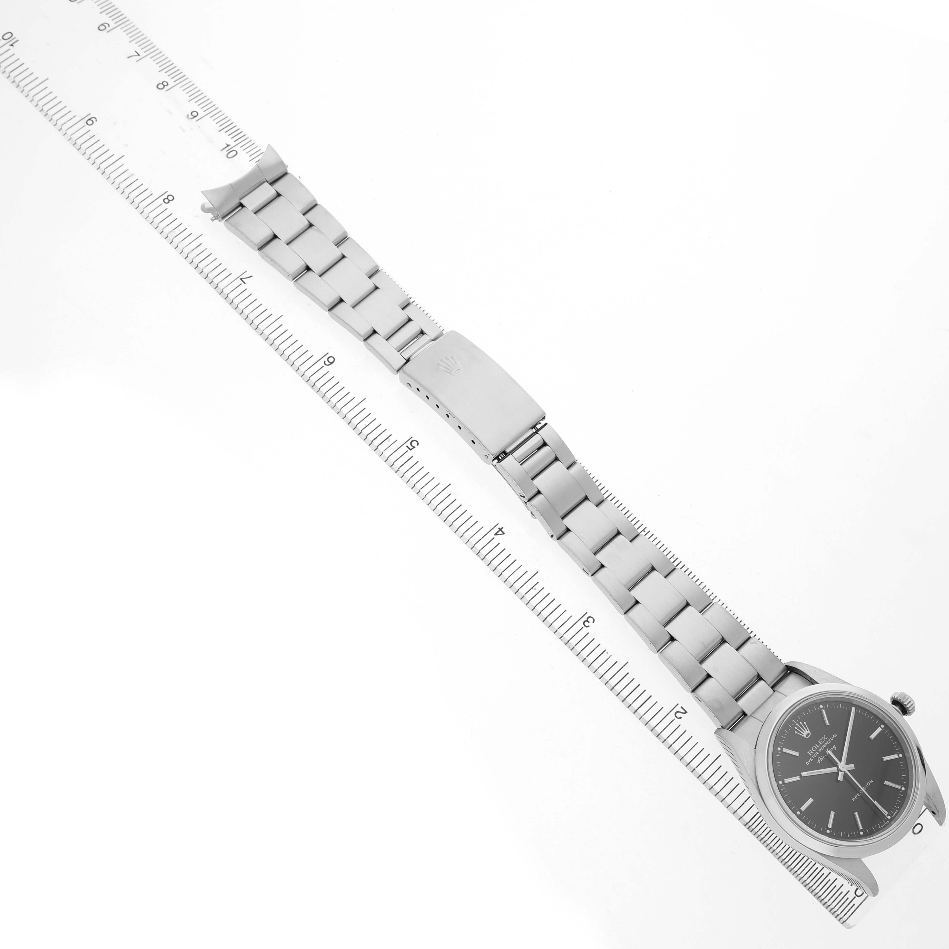 The Rolex Air-King 14000 Men's Stainless Steel Black Dial watch is shown laying flat with the face, bracelet, and clasp visible, aligned with a measuring ruler.
