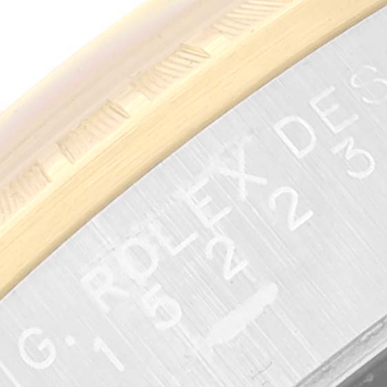 This close-up of a Rolex Date 15223 Men's Steel and Gold (two tone) Champagne Dial 15223 Men's Steel and Gold (two tone) Champagne Dial model watch shows the edge of the bezel and part of the caseback with engravings.
