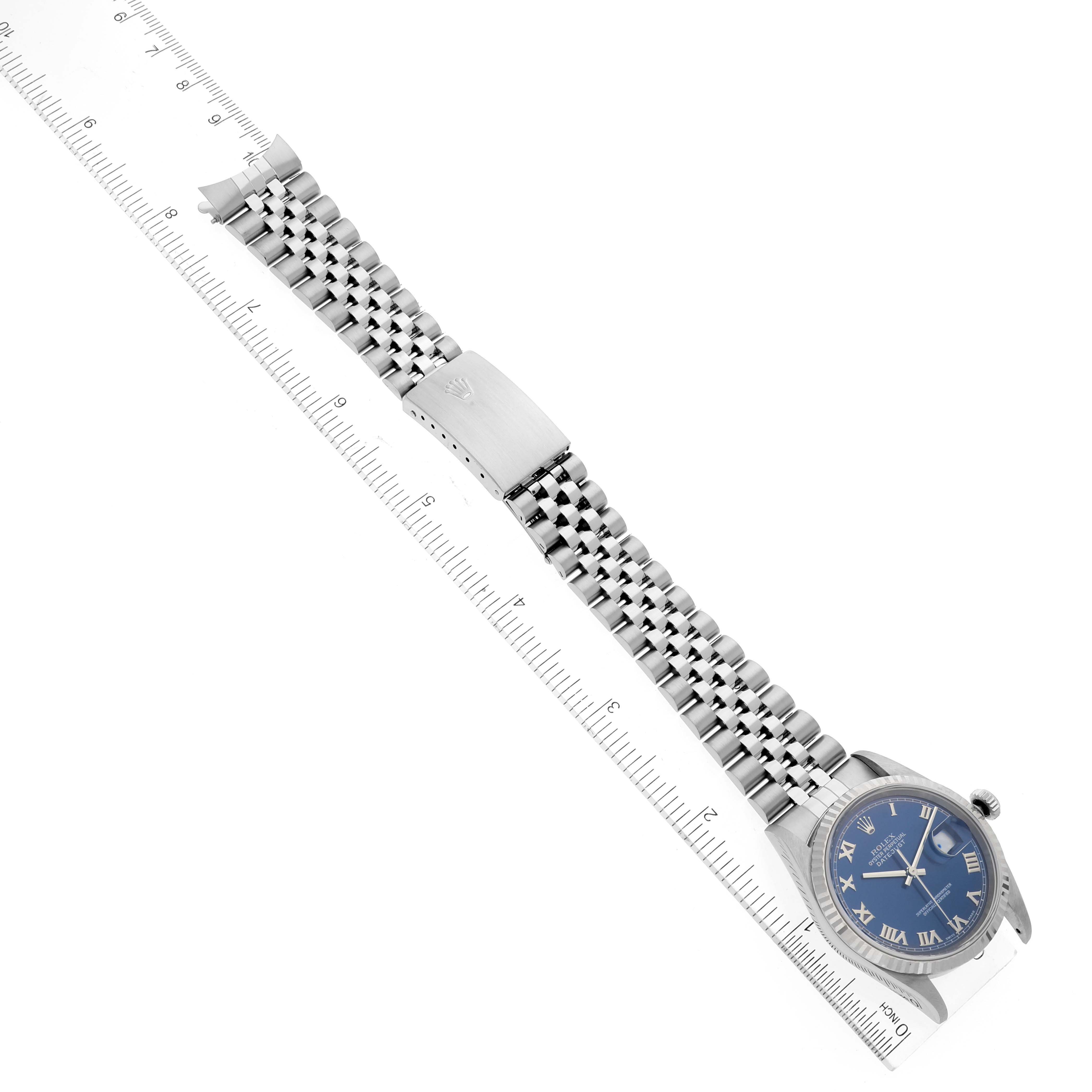 The image shows a top view of a Rolex Datejust 16234 Men's Stainless Steel Blue Dial 16234 Men's Stainless Steel Blue Dial watch with a blue dial and silver Jubilee bracelet, alongside a ruler for scale.