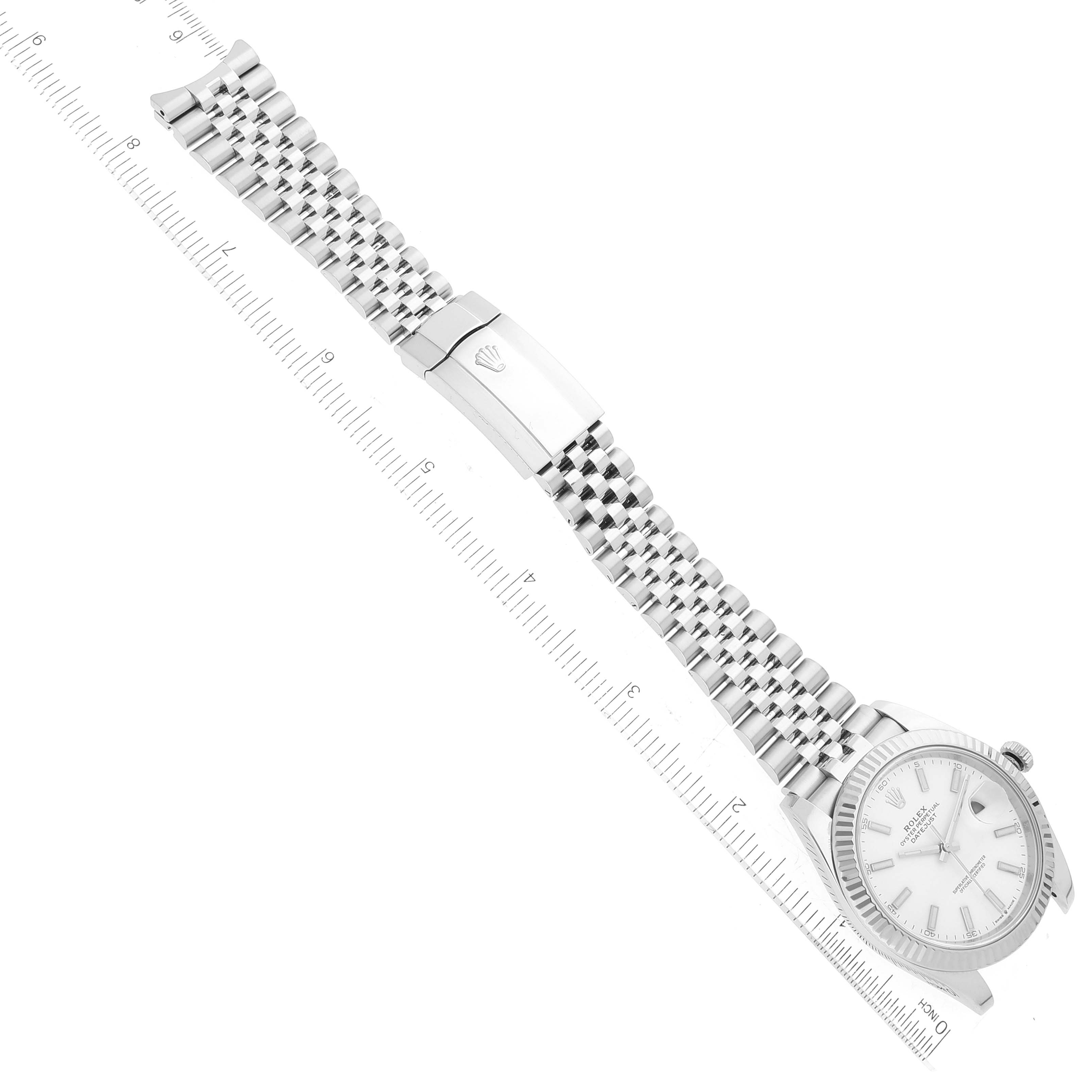 This image shows a Rolex Datejust 41 126334 Men's Stainless Steel White Dial 126334 Men's Stainless Steel White Dial watch laid flat against a ruler, displaying the dial, bracelet, and clasp.