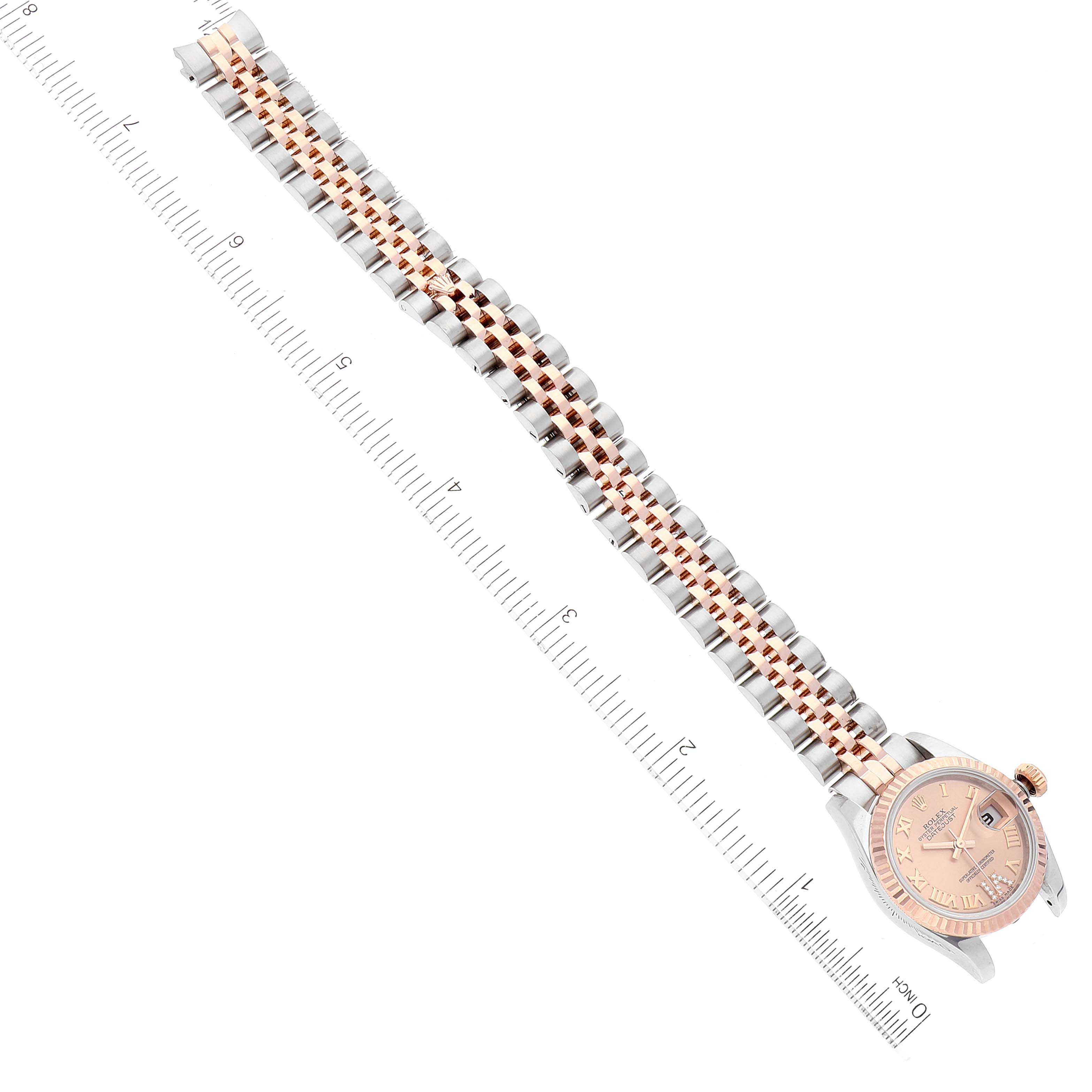 The image shows a top view of a Rolex Datejust 179171 Women
s Steel and Gold (two tone) Pink Dial 179171 Women
s Steel and Gold (two tone) Pink Dial watch, highlighting the watch face, bracelet, and a measuring scale.