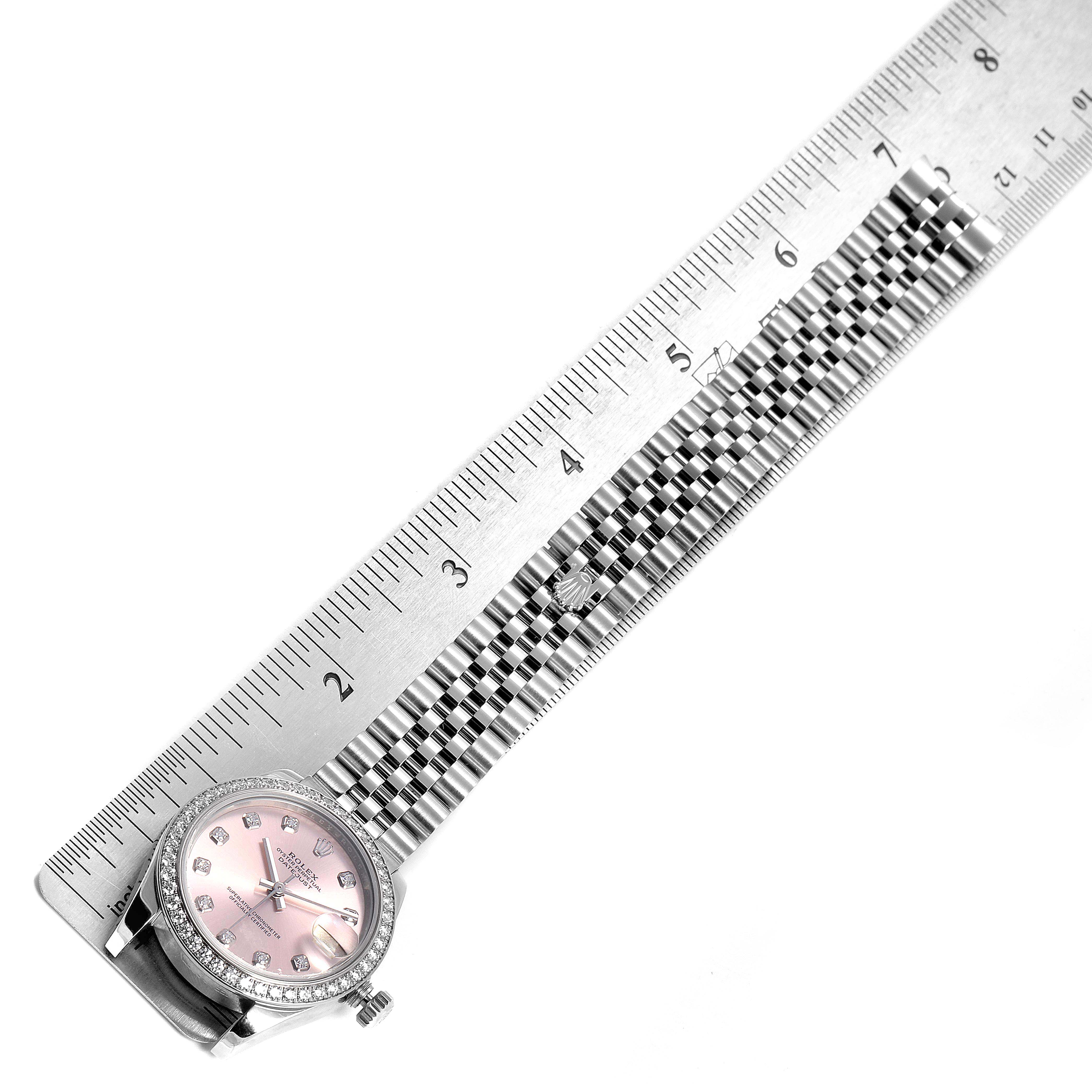 The image shows a Rolex Mid-Size 178384 Women's Stainless Steel Pink Dial 178384 Women's Stainless Steel Pink Dial watch with a pink dial and diamond bezel, measured against a ruler.