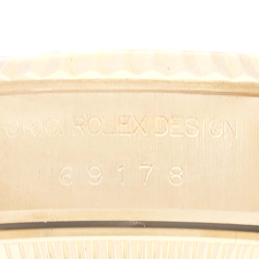 This image shows a close-up of the side of the case of a Rolex President 69178 Women's Yellow Gold Champagne Dial 69178 Women's Yellow Gold Champagne Dial model, revealing its engraved serial number and design details.