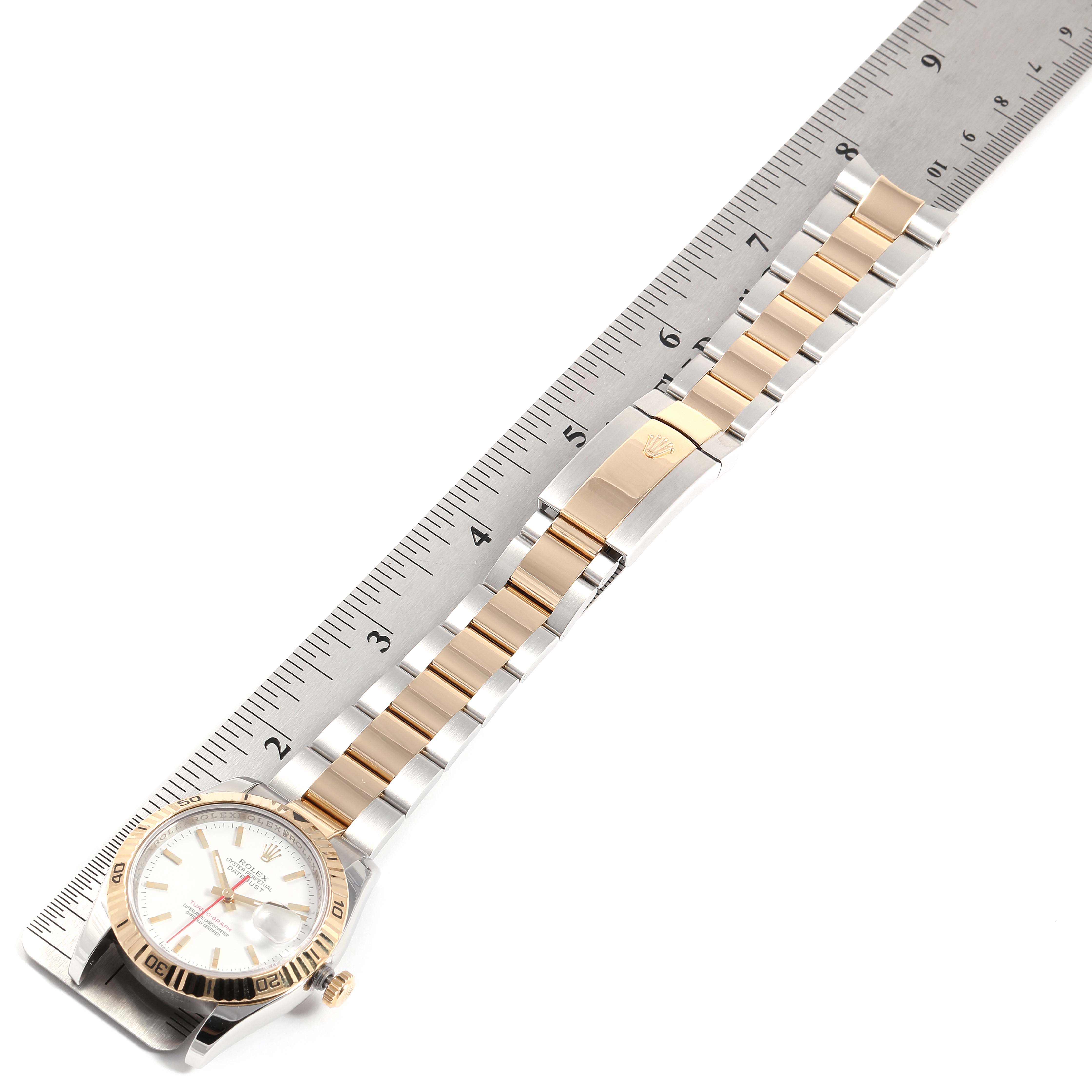 The image shows a top-down view of a Rolex Turn-o-Graph 116263 Men's Steel and Gold (two tone) White Dial 116263 Men's Steel and Gold (two tone) White Dial watch with its face, bezel, bracelet, clasp, and an adjacent ruler.