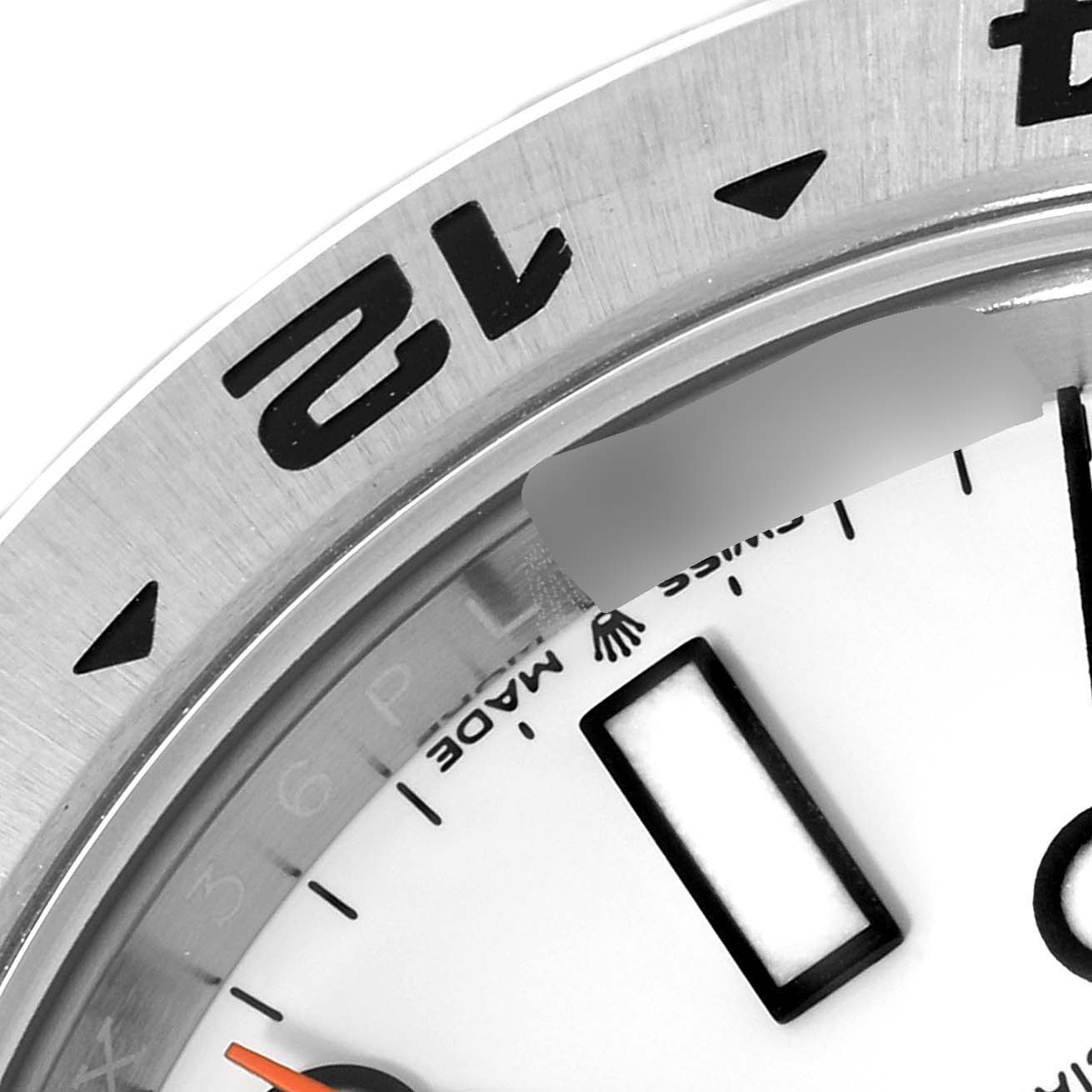The image shows a close-up of the bezel and part of the dial of the Rolex Explorer 226570 Men
s Stainless Steel White Dial 226570 Men
s Stainless Steel White Dial, highlighting the 12 numeral and Swiss Made details.