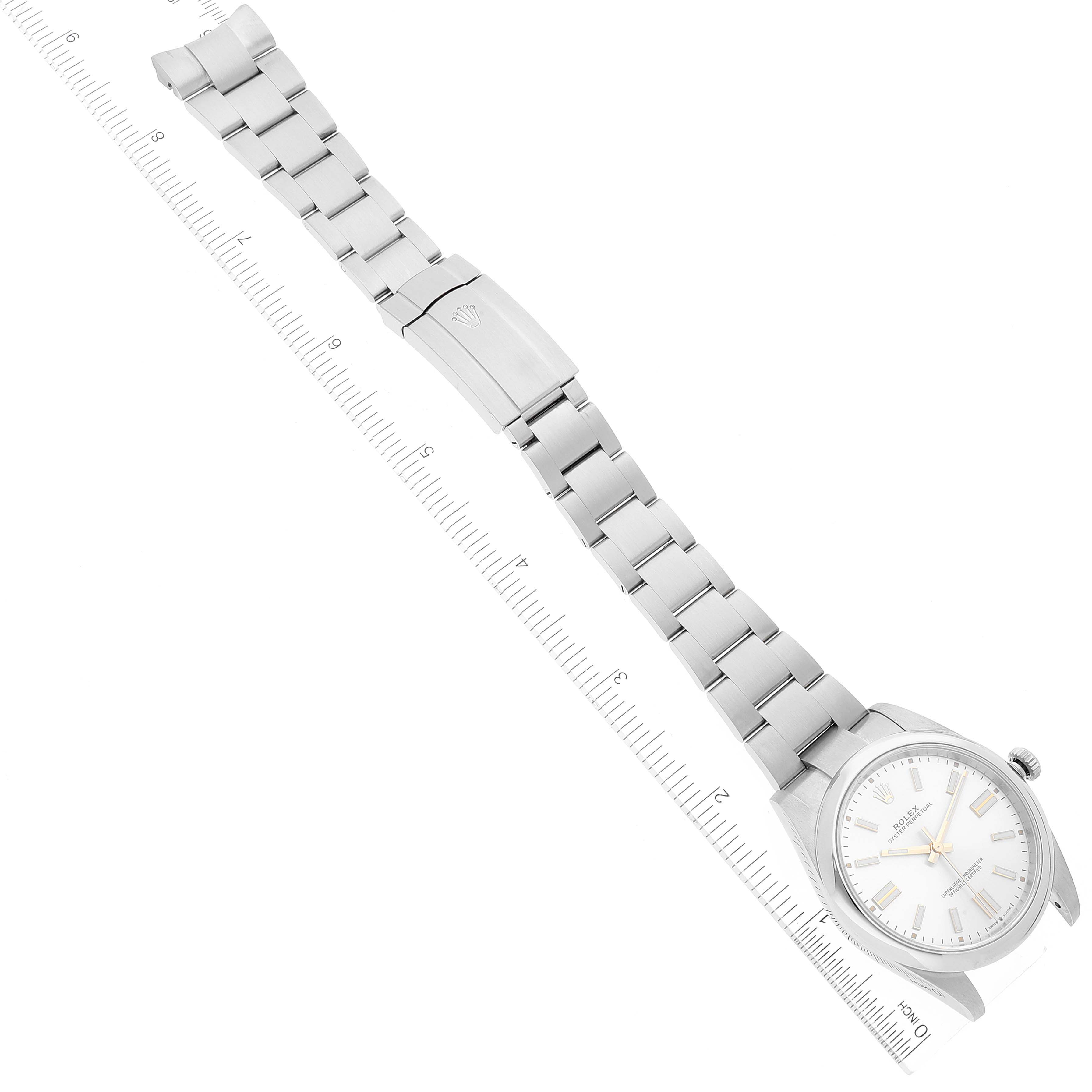 The image shows a Rolex Oyster Perpetual 124300 Men's Stainless Steel Silver Dial 124300 Men's Stainless Steel Silver Dial watch laid flat with its bracelet extended next to a ruler for scale.