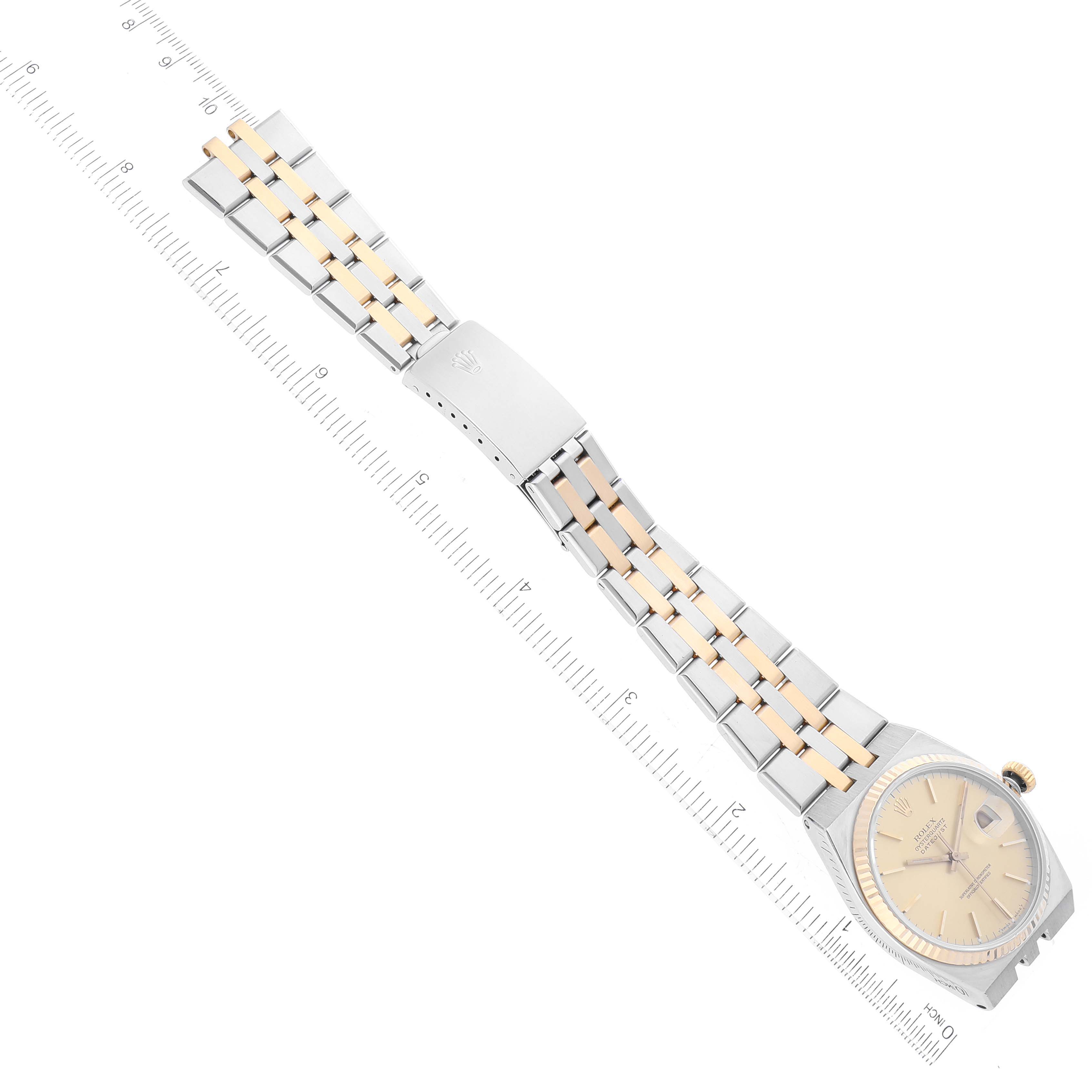 The image shows a top view of a Rolex Oysterquartz 17013 Men
s Steel and Gold (two tone) Champagne Dial 17013 Men
s Steel and Gold (two tone) Champagne Dial watch with its case, dial, and bracelet visible, placed alongside a ruler.