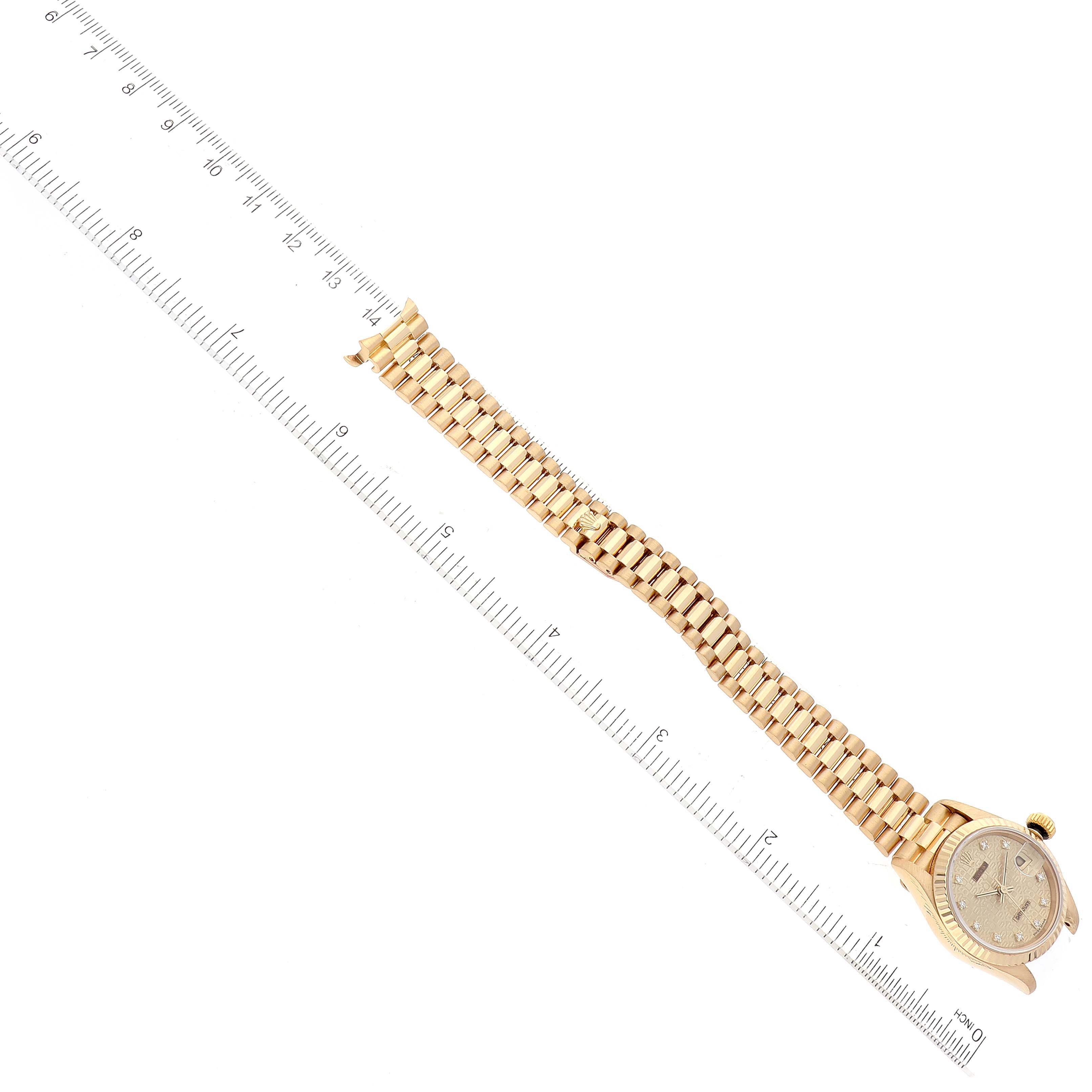 The image shows the Rolex President 69178 Women
s Yellow Gold Champagne Dial 69178 Women
s Yellow Gold Champagne Dial model watch from a top-down angle, displaying the dial and the full length of the bracelet alongside a ruler.