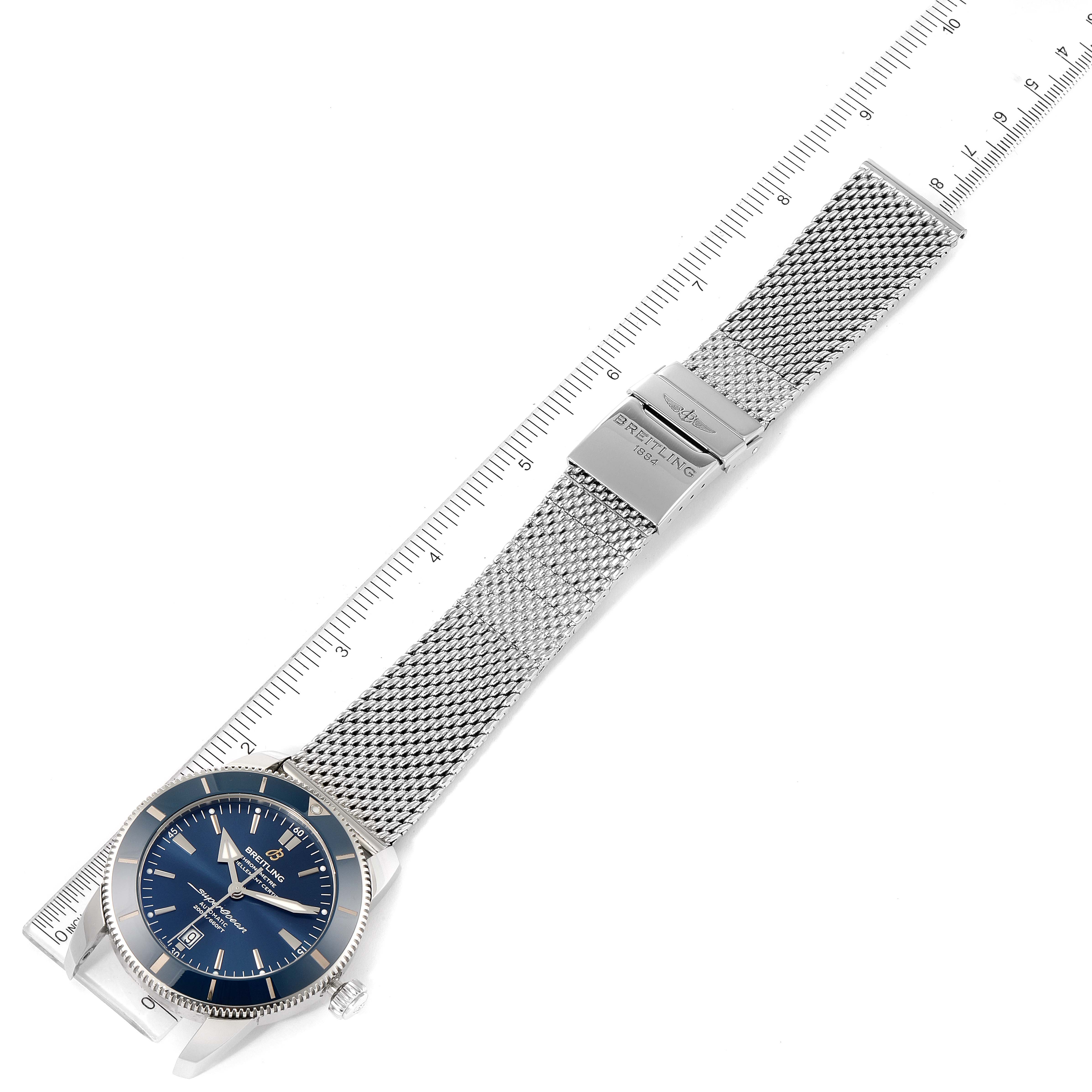 The Breitling Superocean AB202016-C961-152A Men's Stainless Steel Blue Dial AB202016-C961-152A Men's Stainless Steel Blue Dial watch is shown from an overhead angle, displaying its face, mesh bracelet, clasp, and part of a ruler for scale.