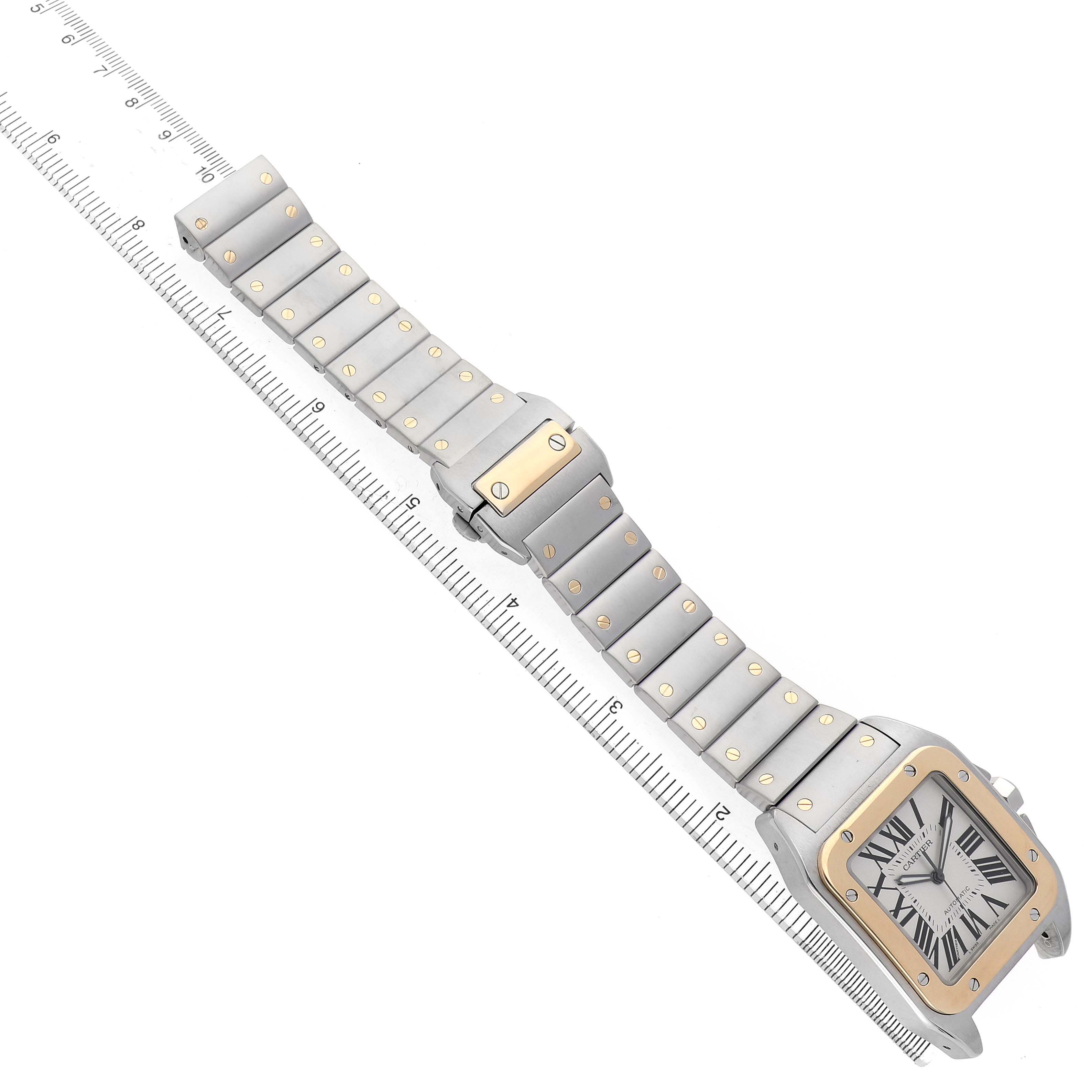 The image shows a Cartier Santos W200728G Men's Stainless Steel Silver Dial watch laid flat with its face, bezel, and entire metal bracelet visible alongside a ruler for scale.