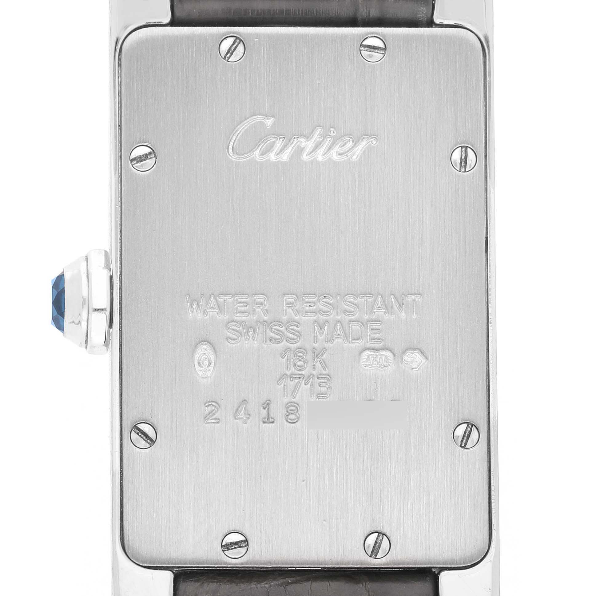 This image shows the back of the Cartier Tank Americaine W2605129 Women's White Gold Grey Dial watch, highlighting the metal case, screws, and gemstone-adorned crown.