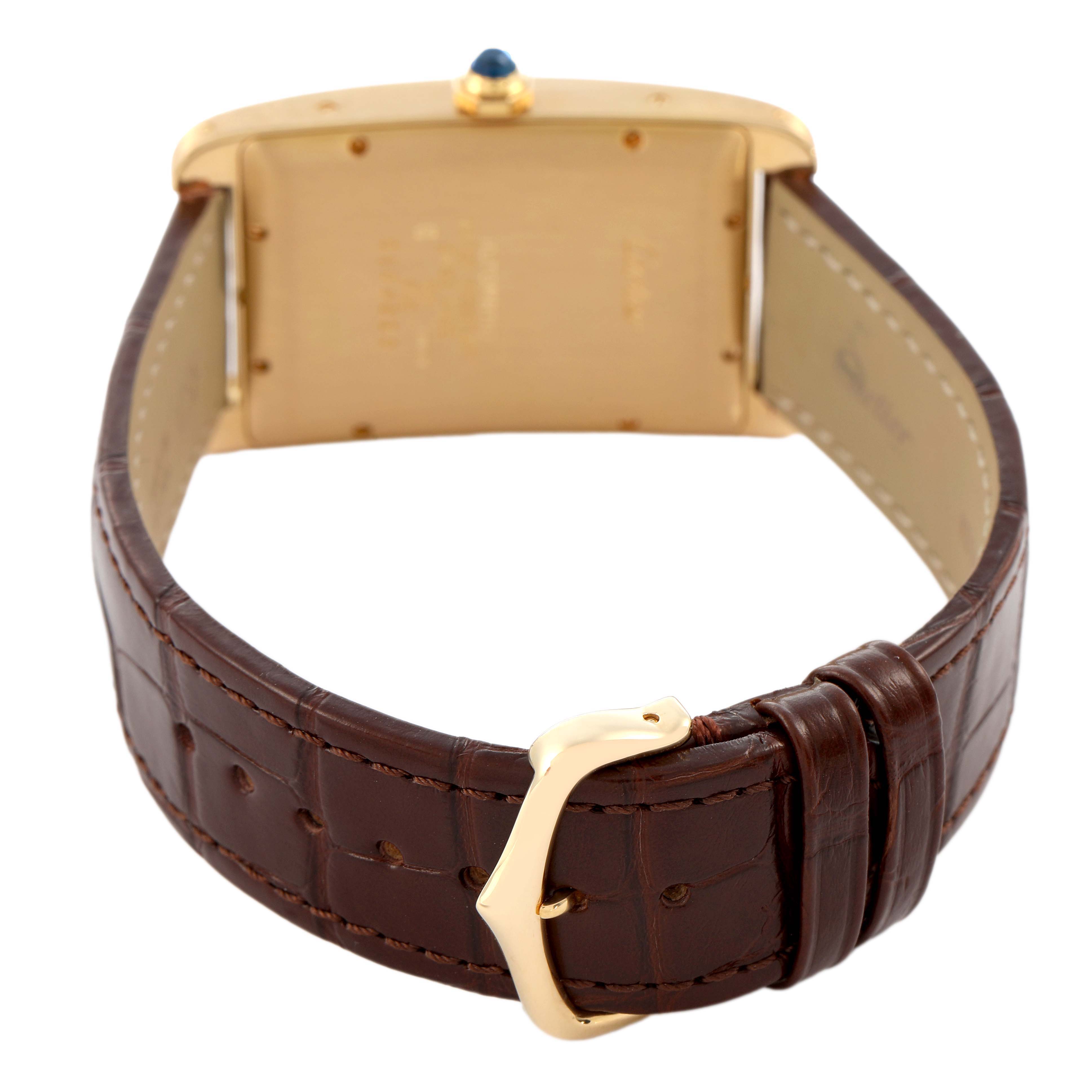 The Cartier Tank Américaine watch is shown from the back, highlighting the case, crown, and leather strap with a buckle.