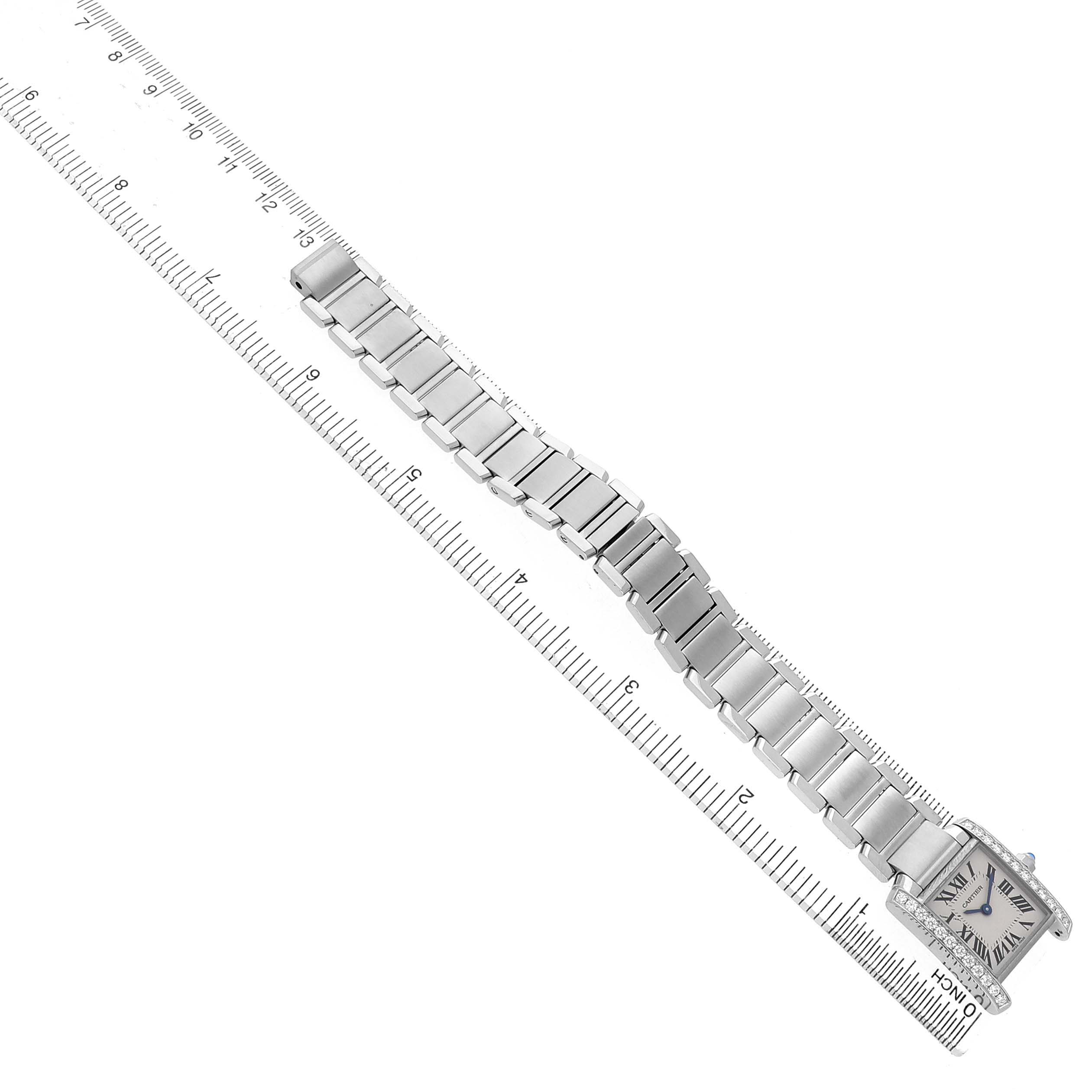 The Cartier Tank Française watch is shown from a top-down angle, displaying its entire bracelet and face next to a ruler.