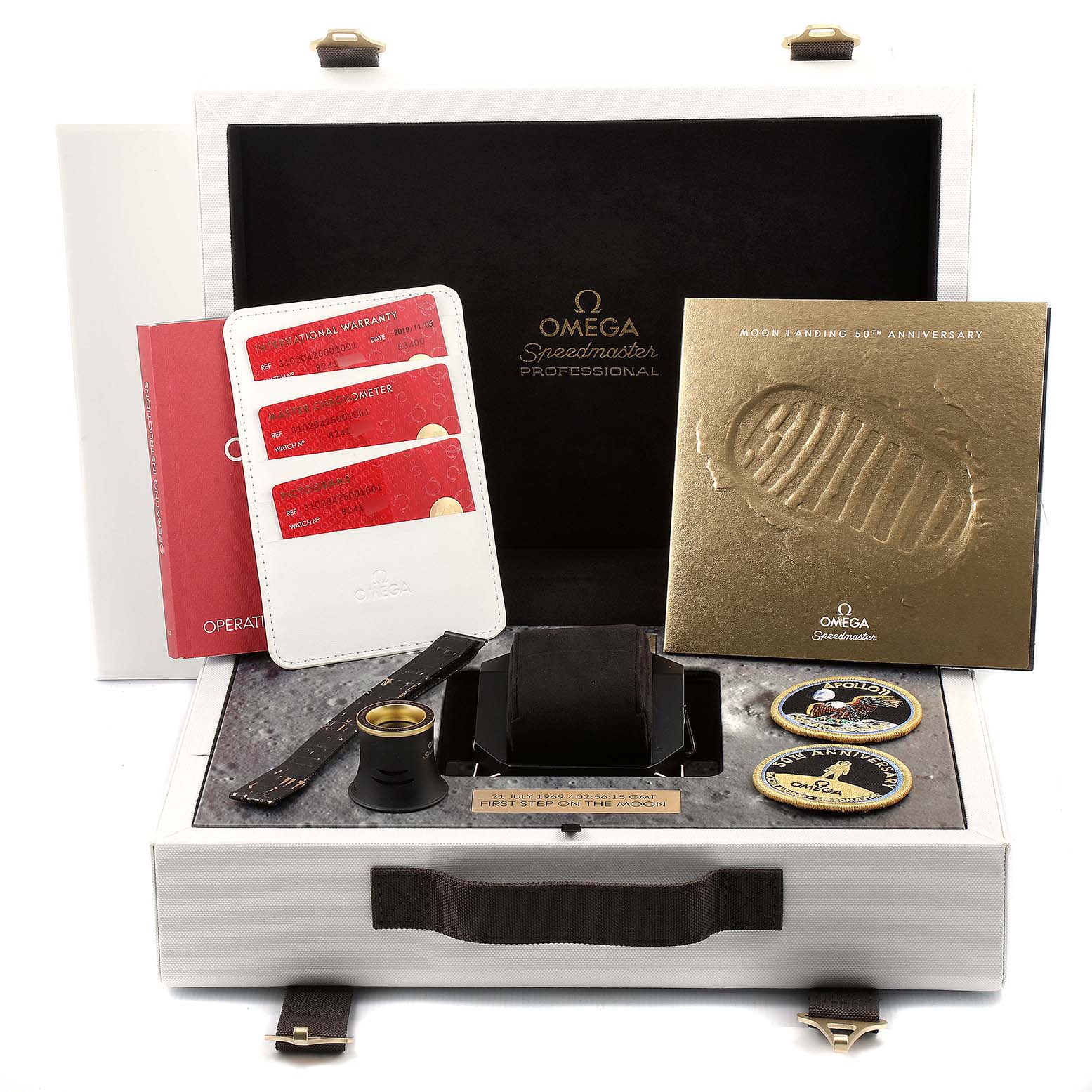 The image shows an Omega Speedmaster 310.20.42.50.01.001 Men's Stainless Steel Grey Dial 310.20.42.50.01.001 Men's Stainless Steel Grey Dial watch box, including warranty cards, a booklet, strap, loupe, and commemorative items.