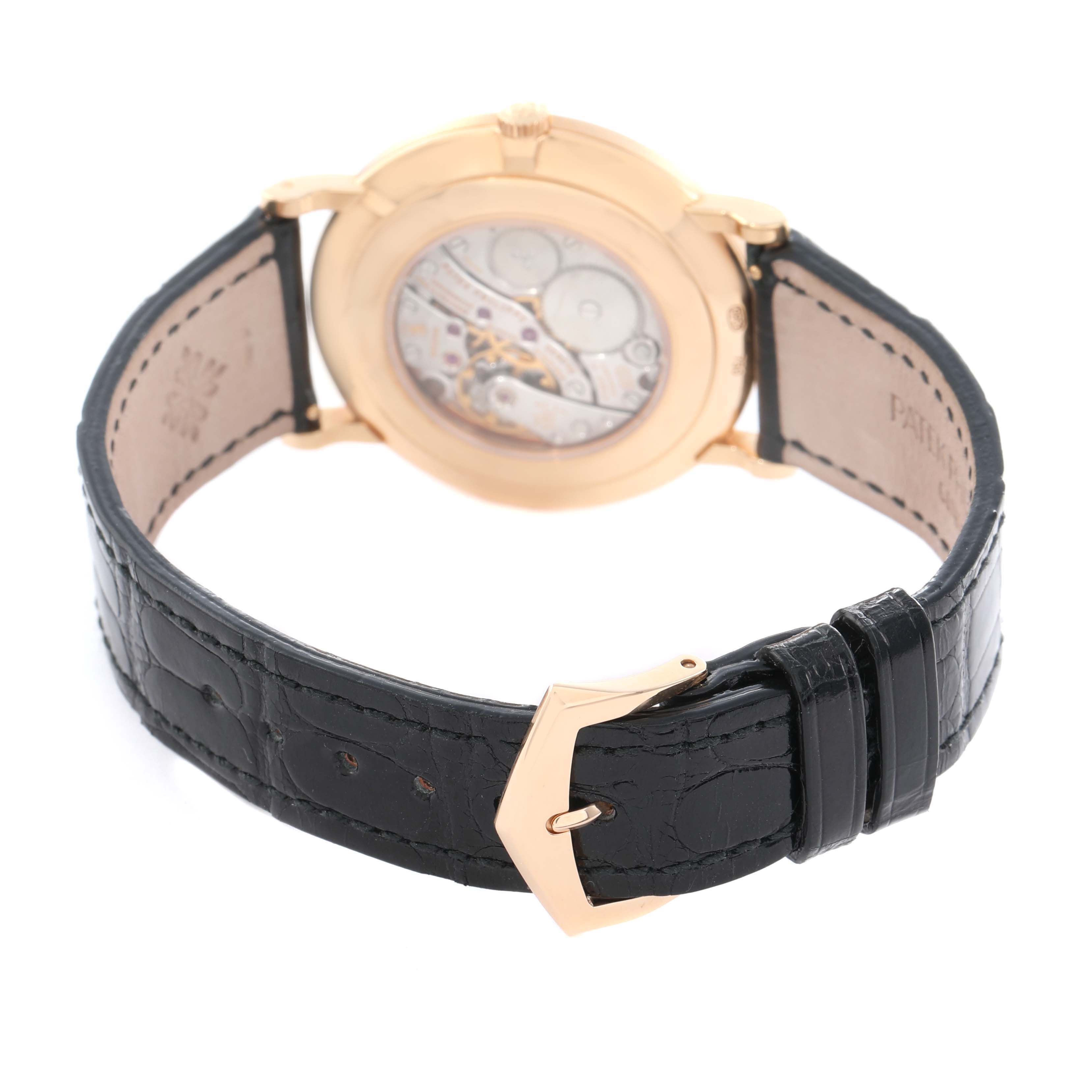 The Calatrava model by Patek Philippe is shown from the back, highlighting the movement through the transparent case back and the black leather strap.