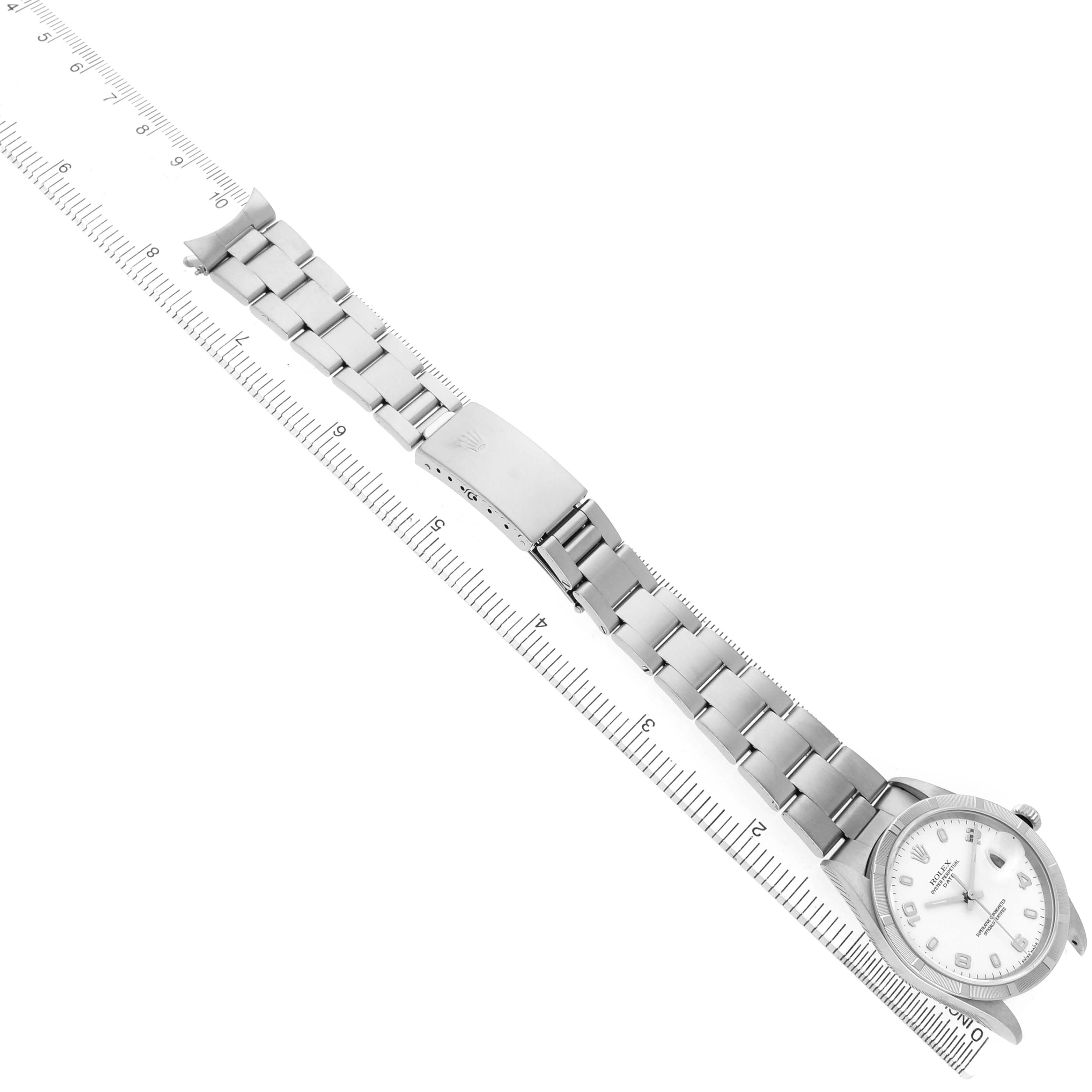 The image shows a Rolex Date 15210 Men's Stainless Steel White Dial model watch laid flat on a ruler, highlighting the bracelet and clasp.