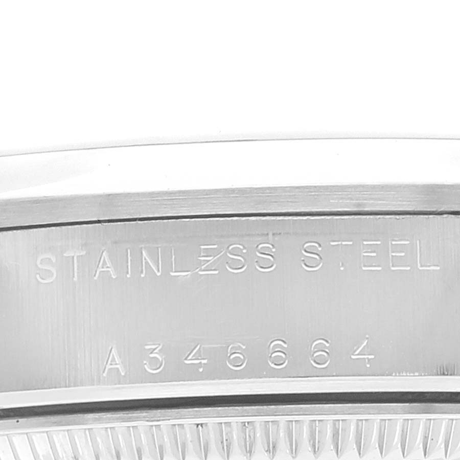 This image shows a close-up of the side of the case of a Mid-Size Rolex watch, featuring "STAINLESS STEEL" and a serial number.