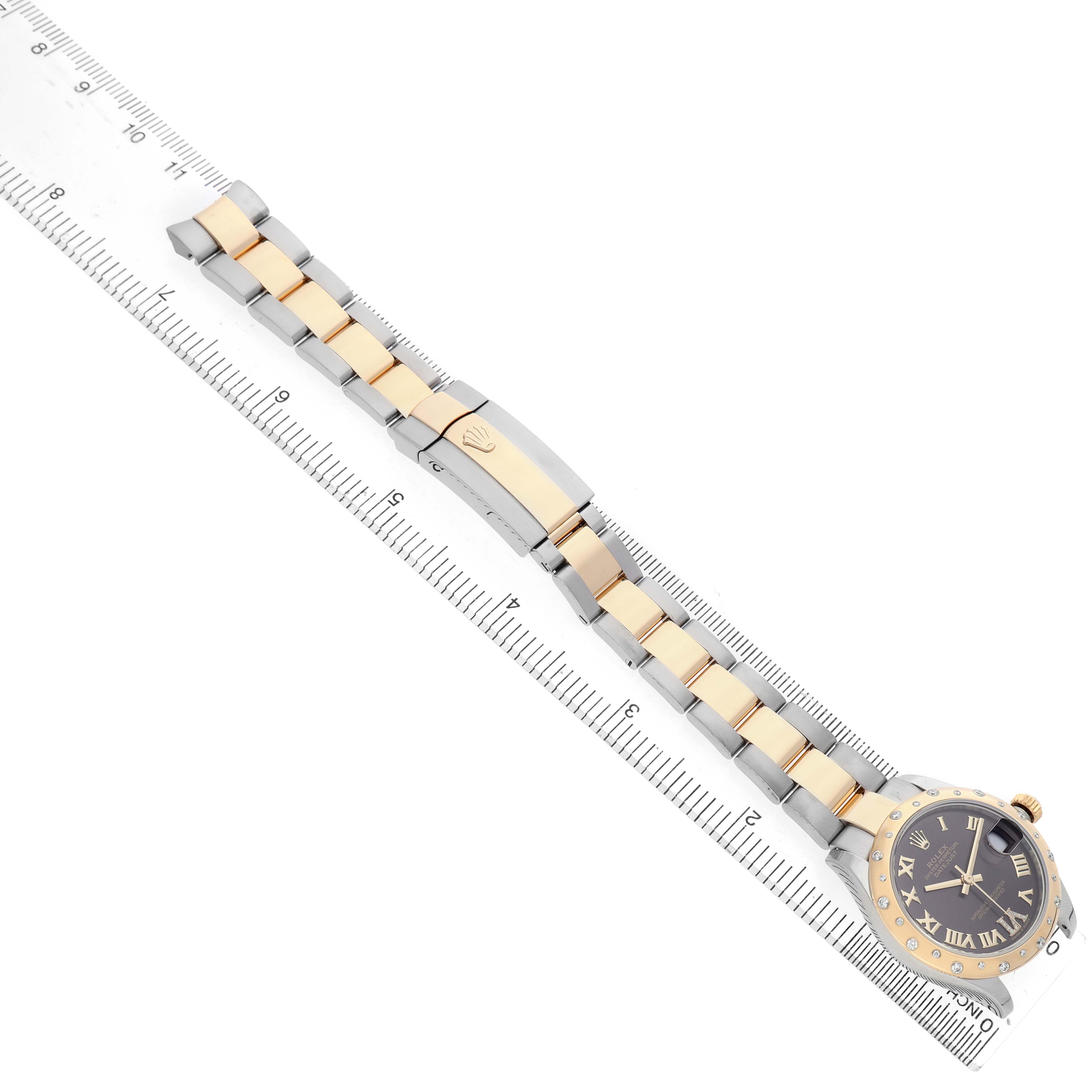 The Rolex Datejust 278343 Women's Steel and Gold (two tone) Grey Dial watch is shown with its two-tone bracelet and clasp, placed diagonally alongside a ruler.