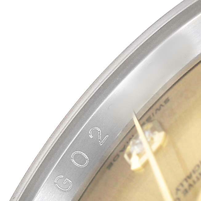 The image shows a close-up of the bezel and dial of a Rolex Datejust 116203 Men's Steel and Gold (two tone) Champagne Dial, highlighting engraved markings.